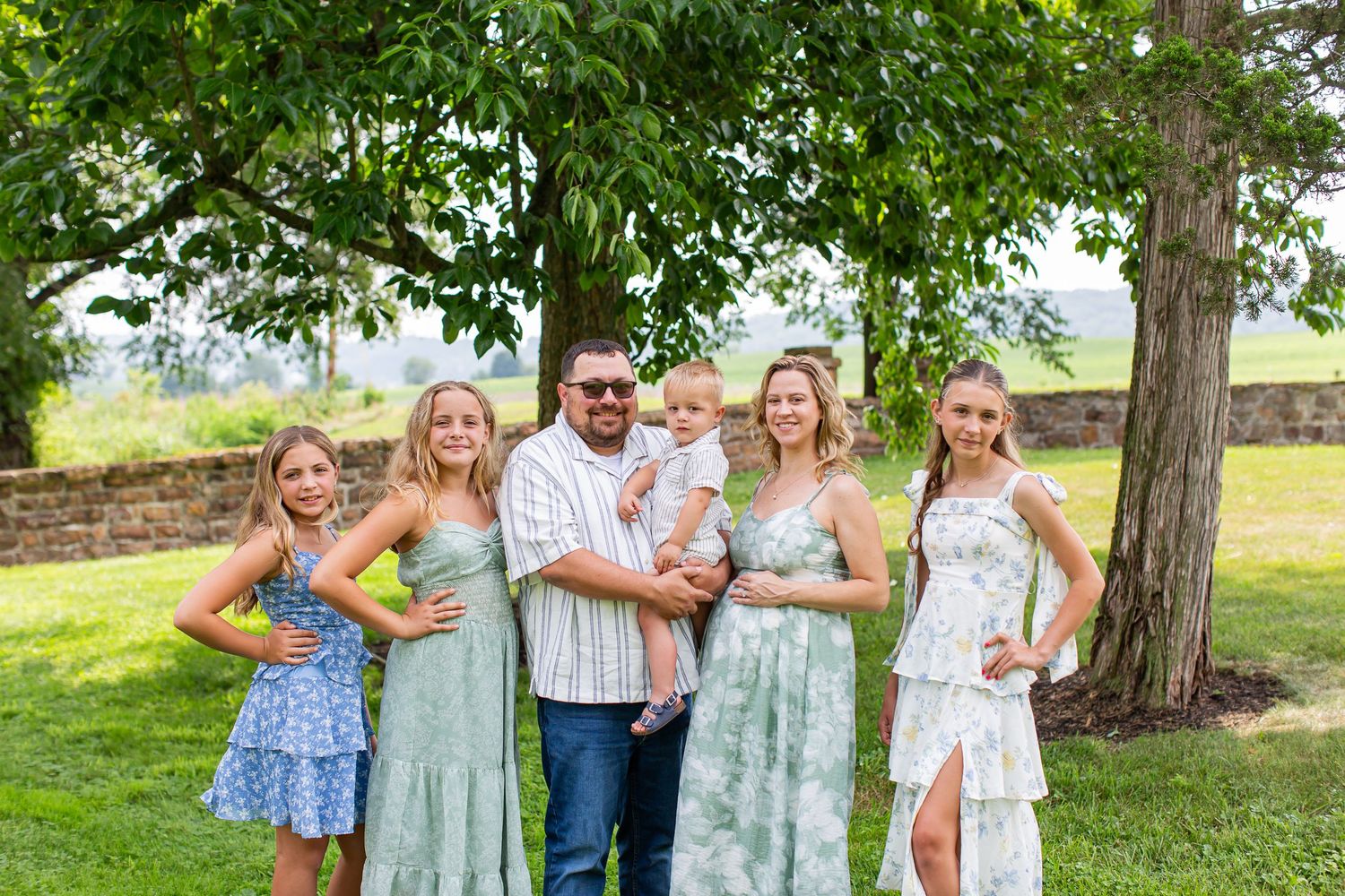 Family posing together on the lawn beneath a large tree.