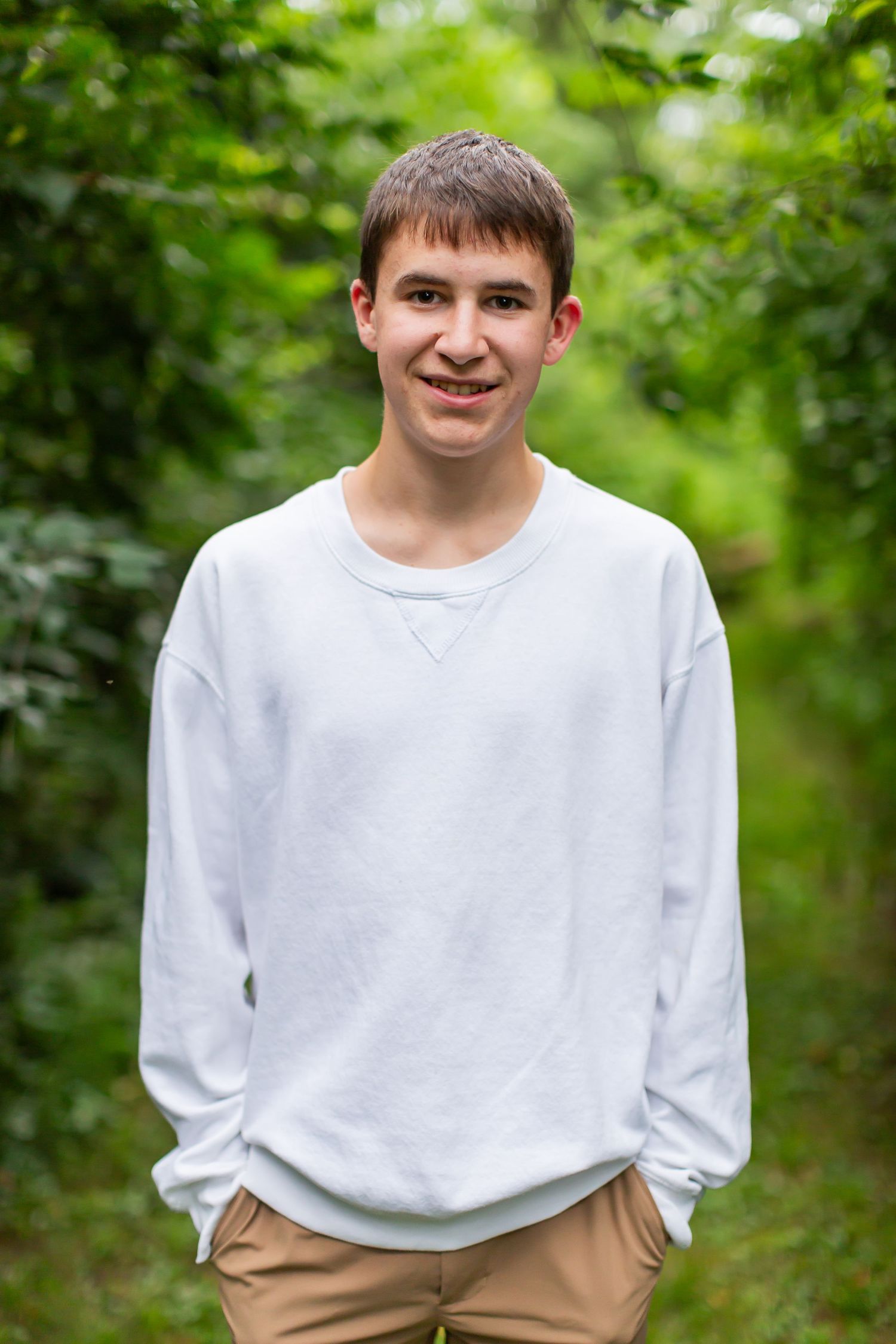 Young man in a light shirt smiling for an outdoor portrait.