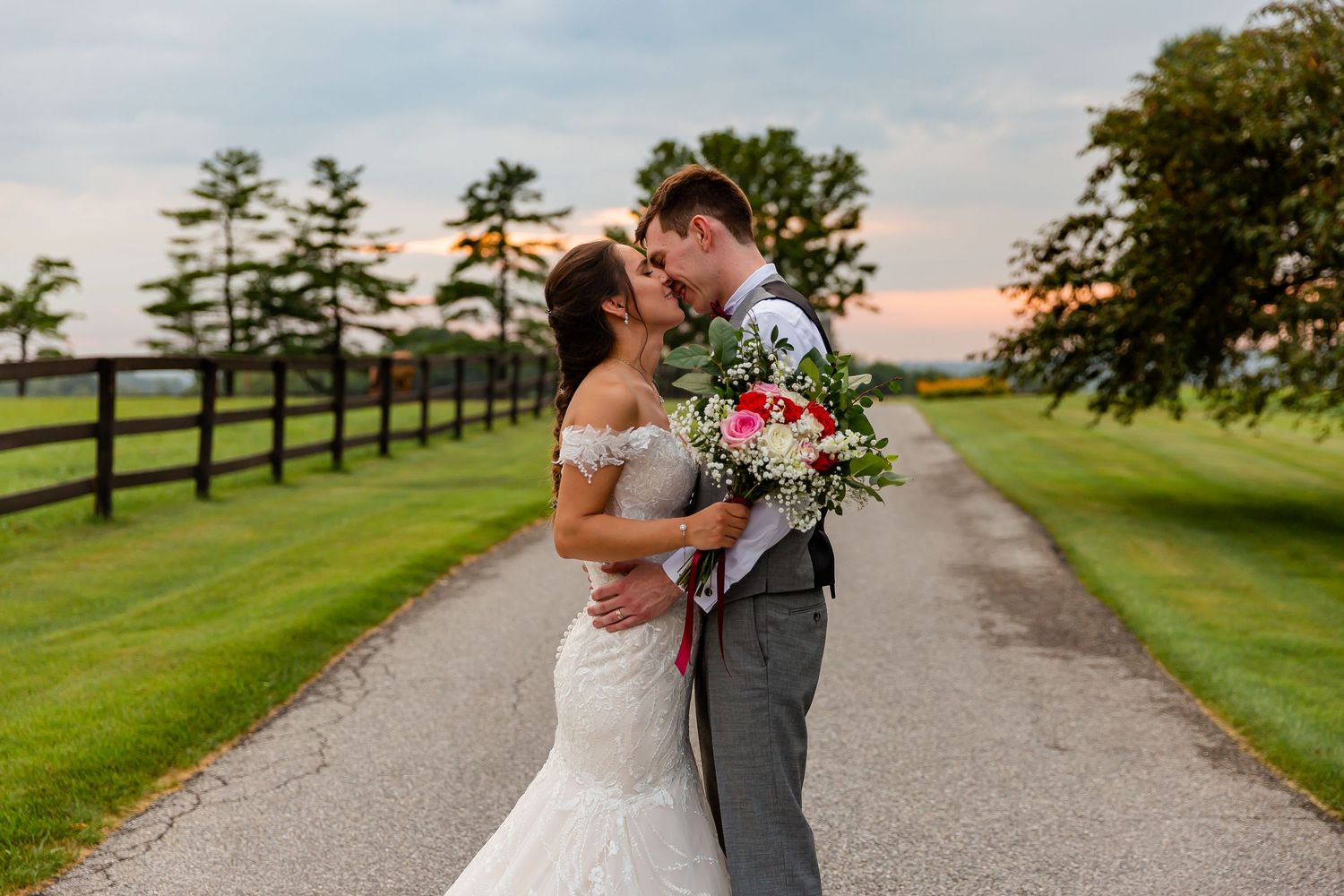 Bride and groom embracing on a country lane at sunset.