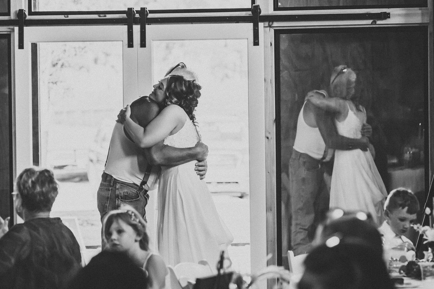Black-and-white photograph of a bride embracing a loved one during her wedding day.