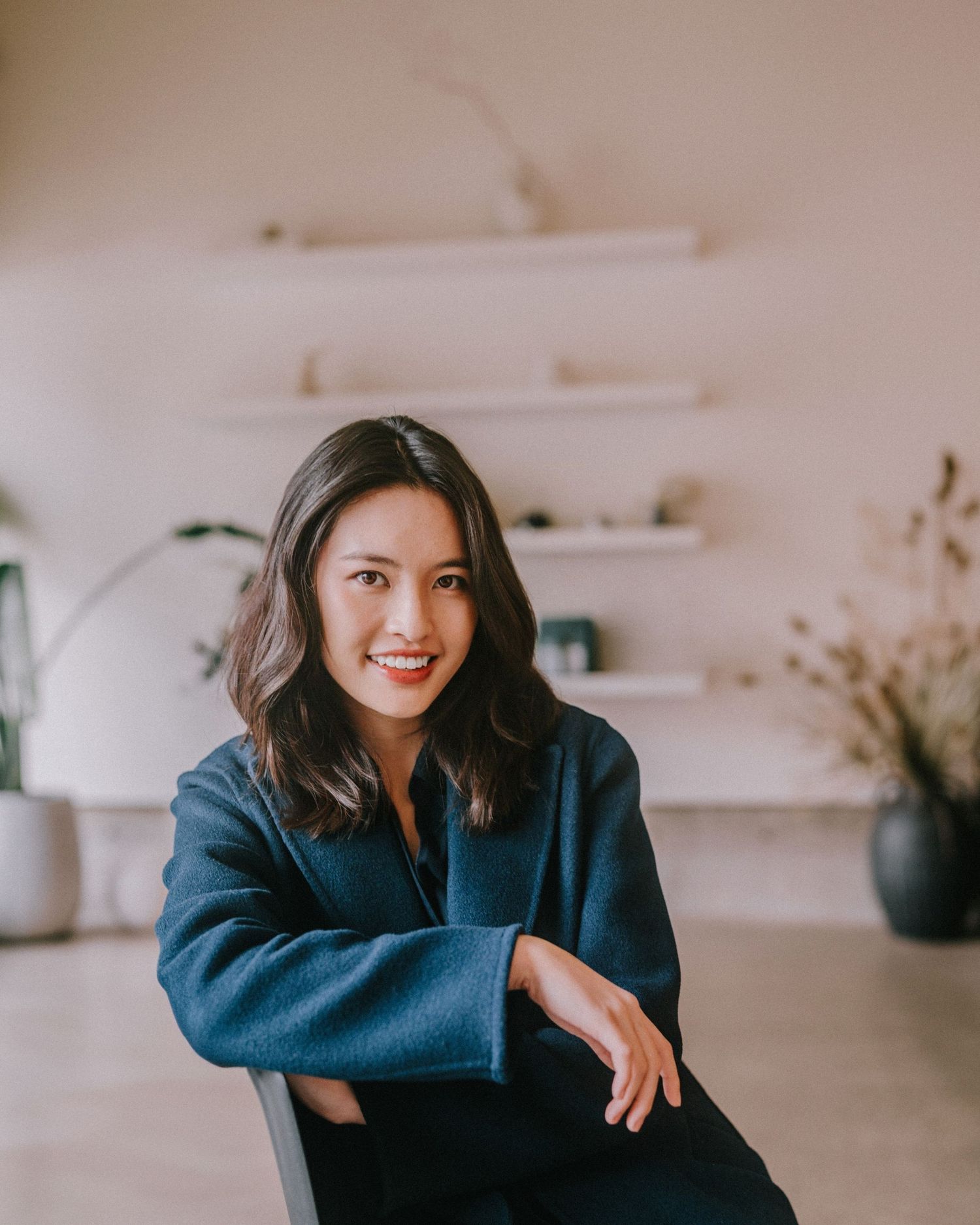 A lifestyle portrait in a minimalist interior with floating shelves and dried flowers.