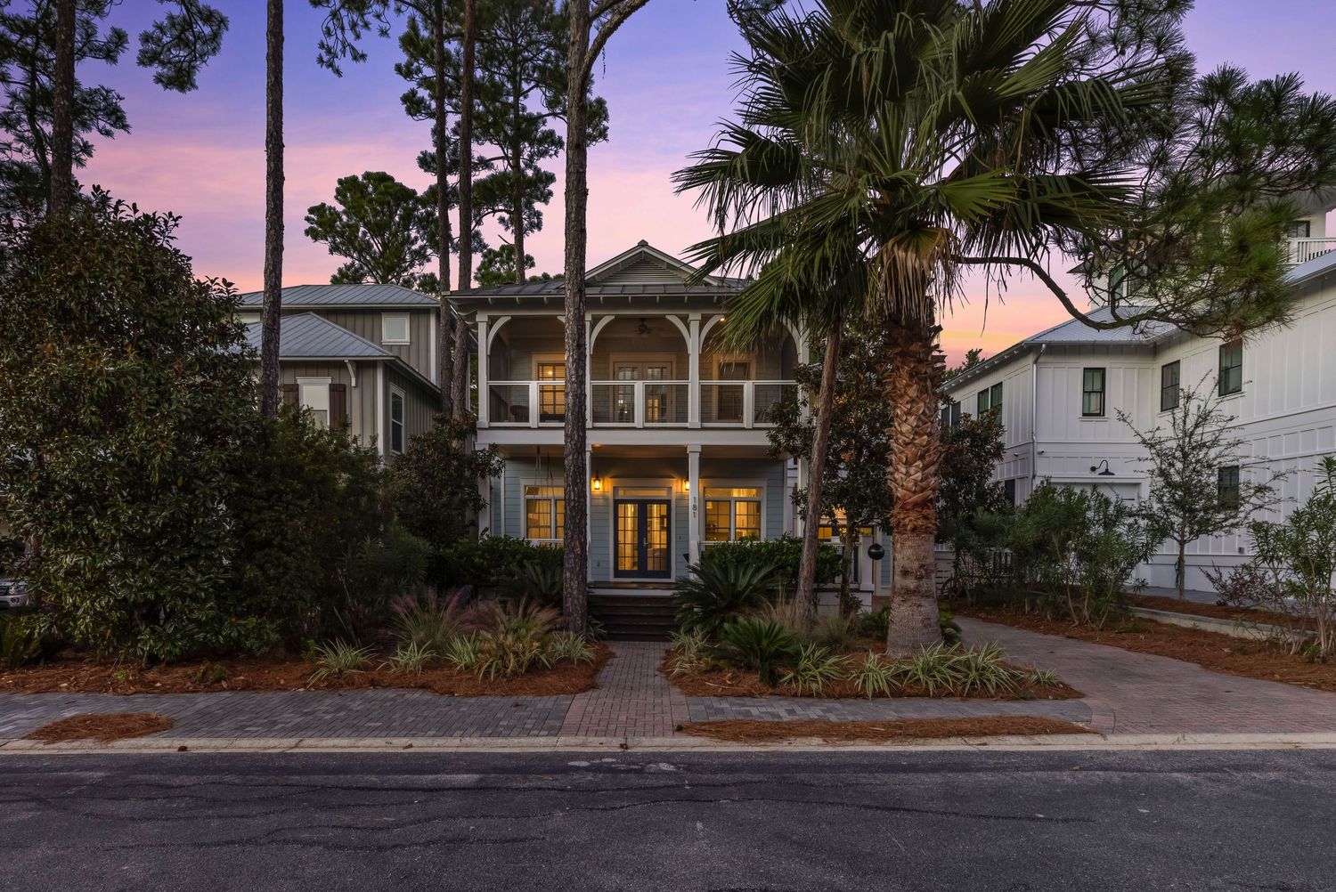 Twilight exterior of luxury coastal home surrounded by palm trees, captured by Coast Captured 30A Real Estate Photography