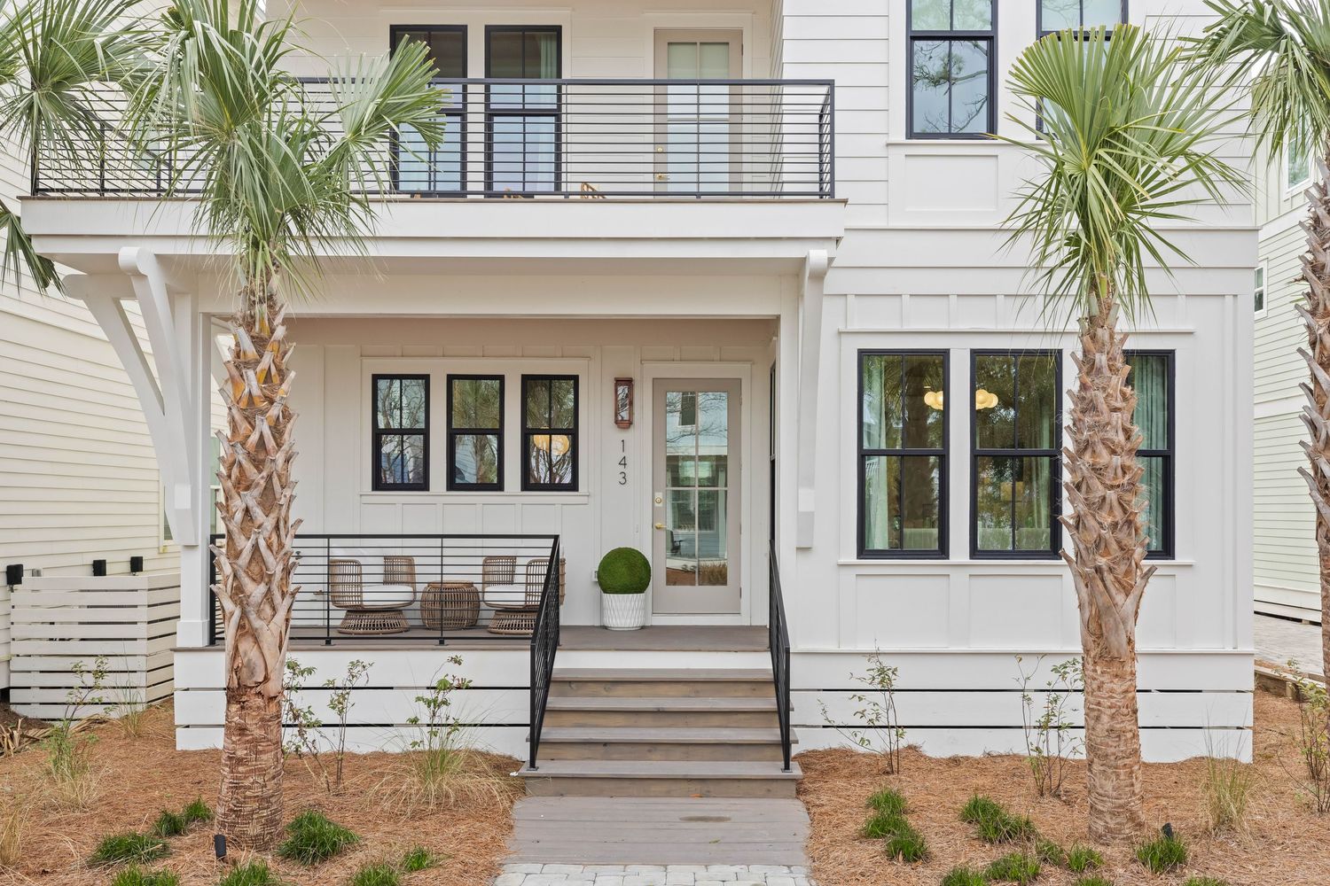 Modern white coastal home with palm trees and front porch, exterior photo by Coast Captured Real Estate Photography Emerald Coast FL