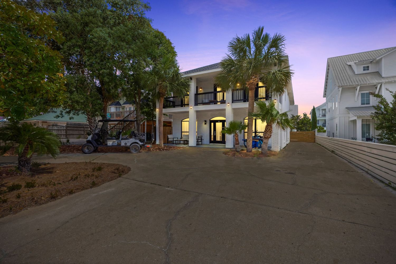 Twilight exterior of luxury coastal home with warm lighting and palm trees, captured by Coast Captured 30A real estate photography