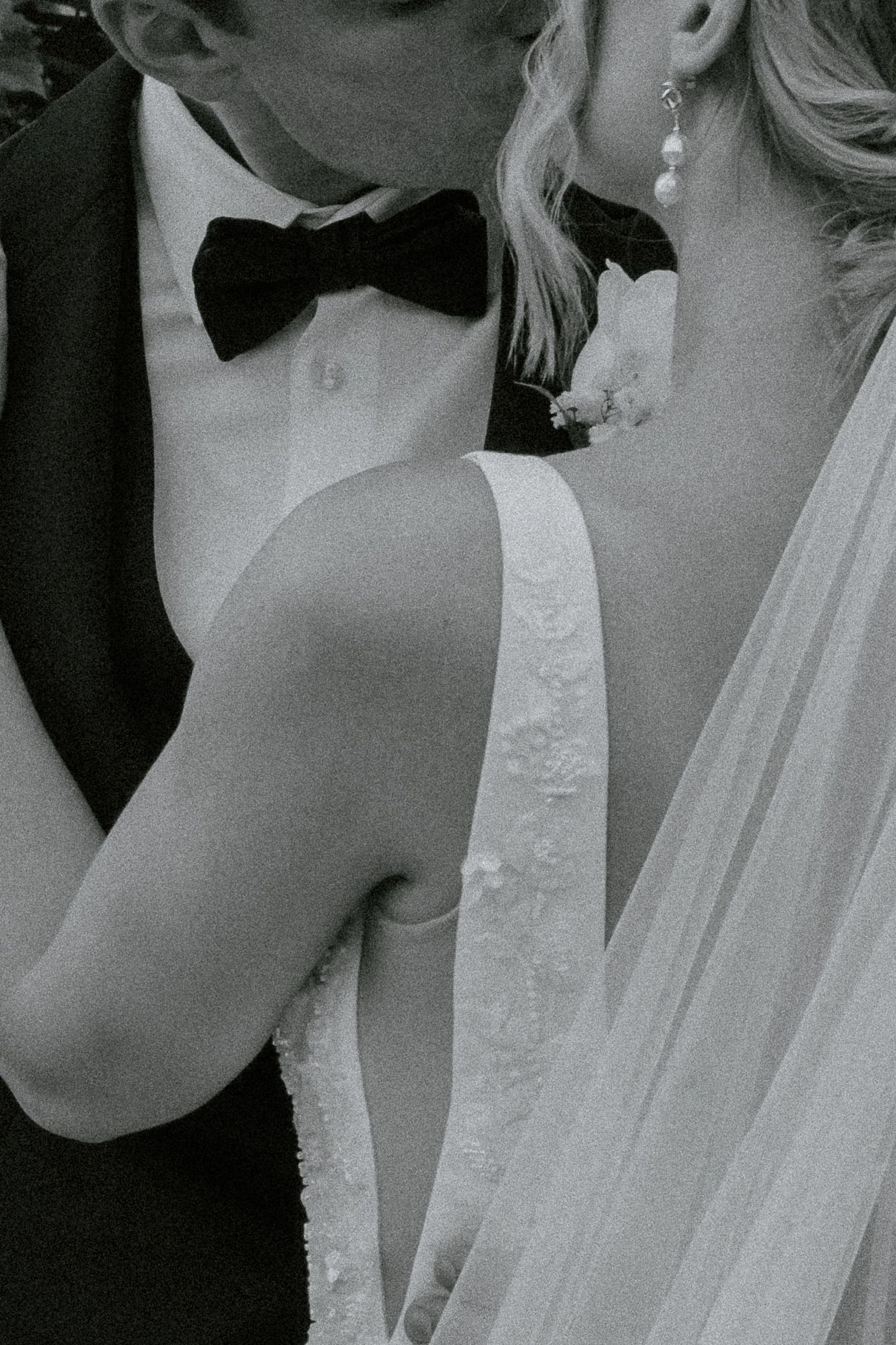 Artful black and white close-up of luxury wedding attire showing bow tie and bridal details of a couple madly in love.