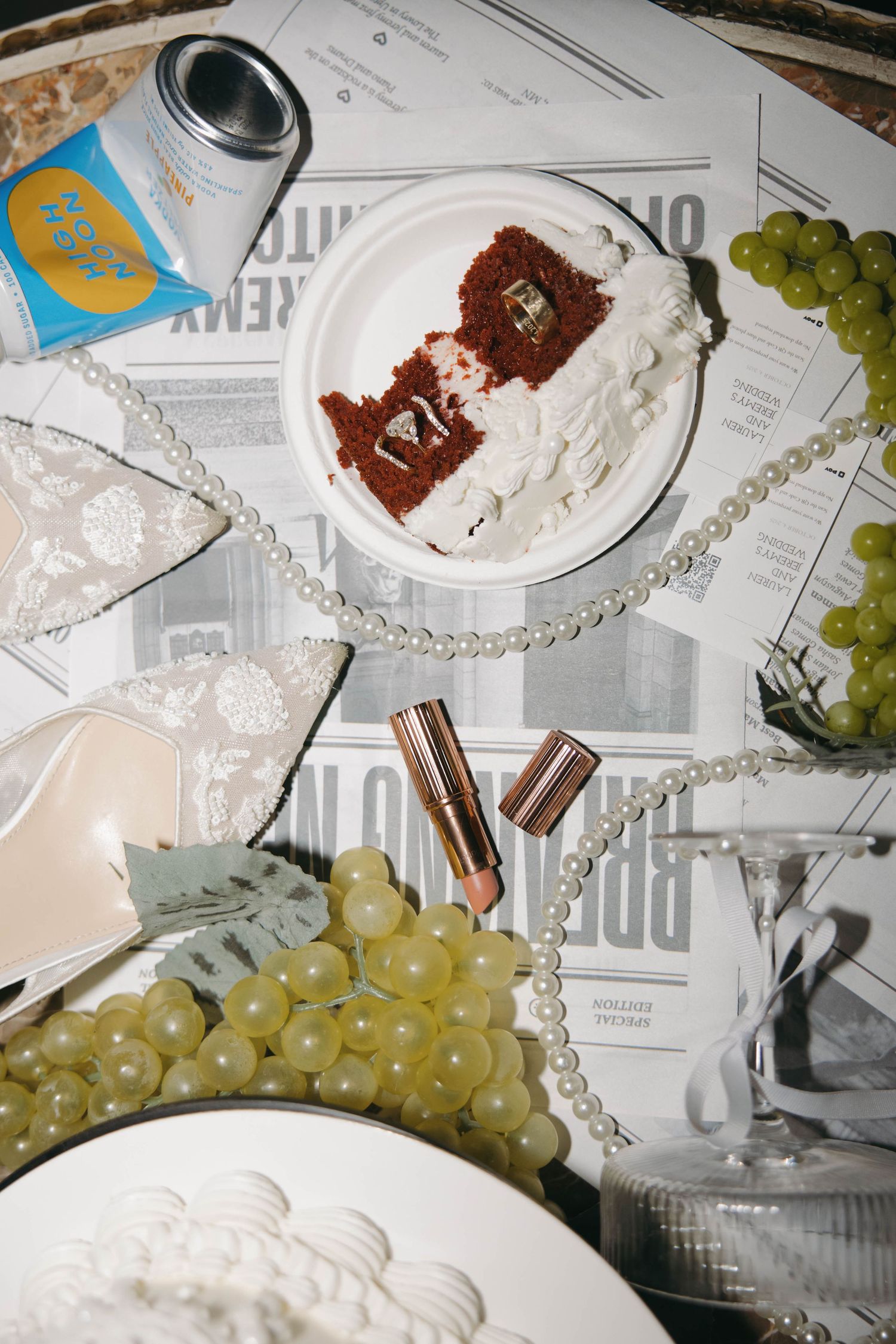 Chocolate cake slices with pearl necklace and green grapes arranged on white plates against newspaper background.