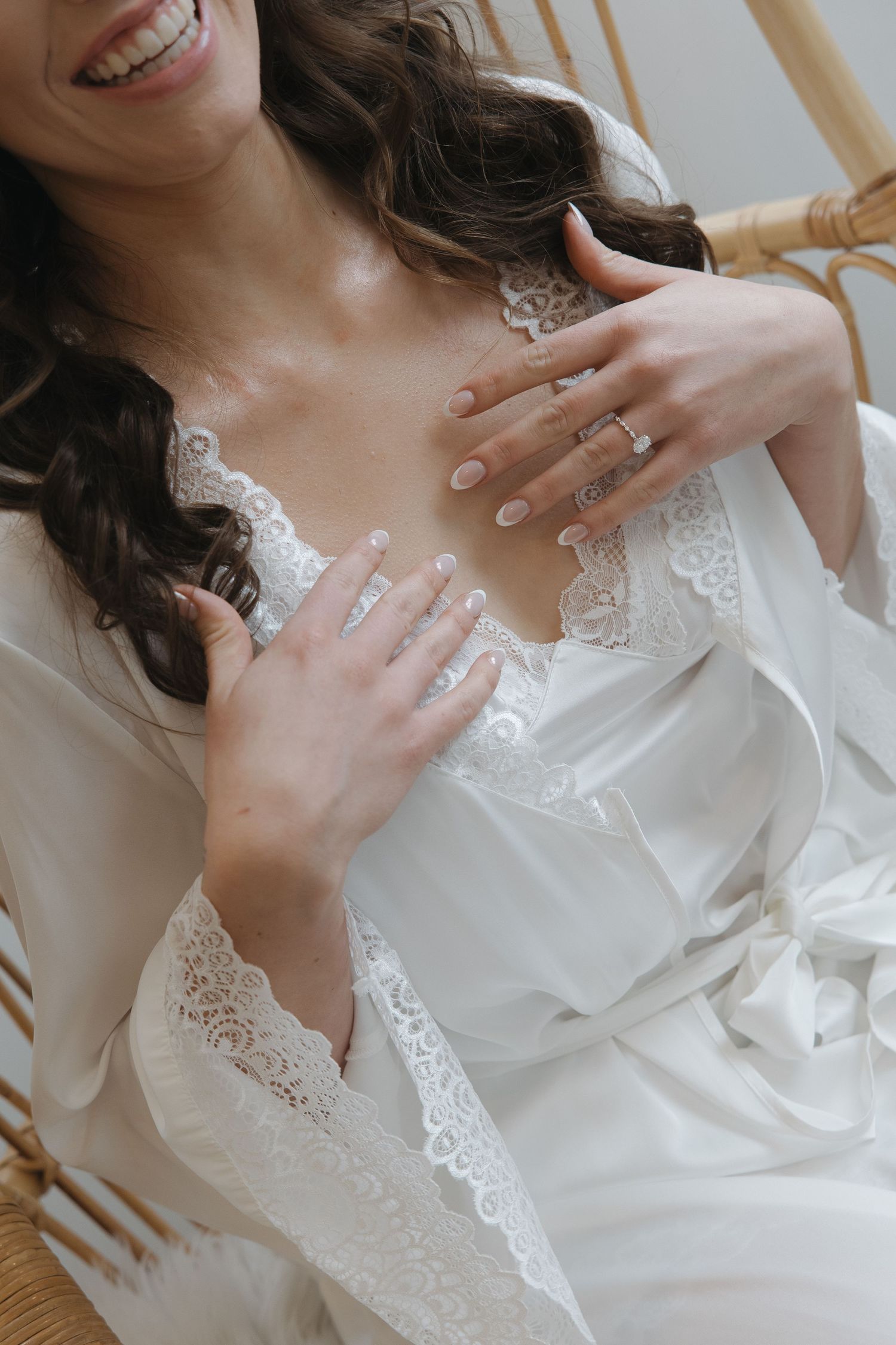 Delicate white lace robe detail with hands showing wedding rings.