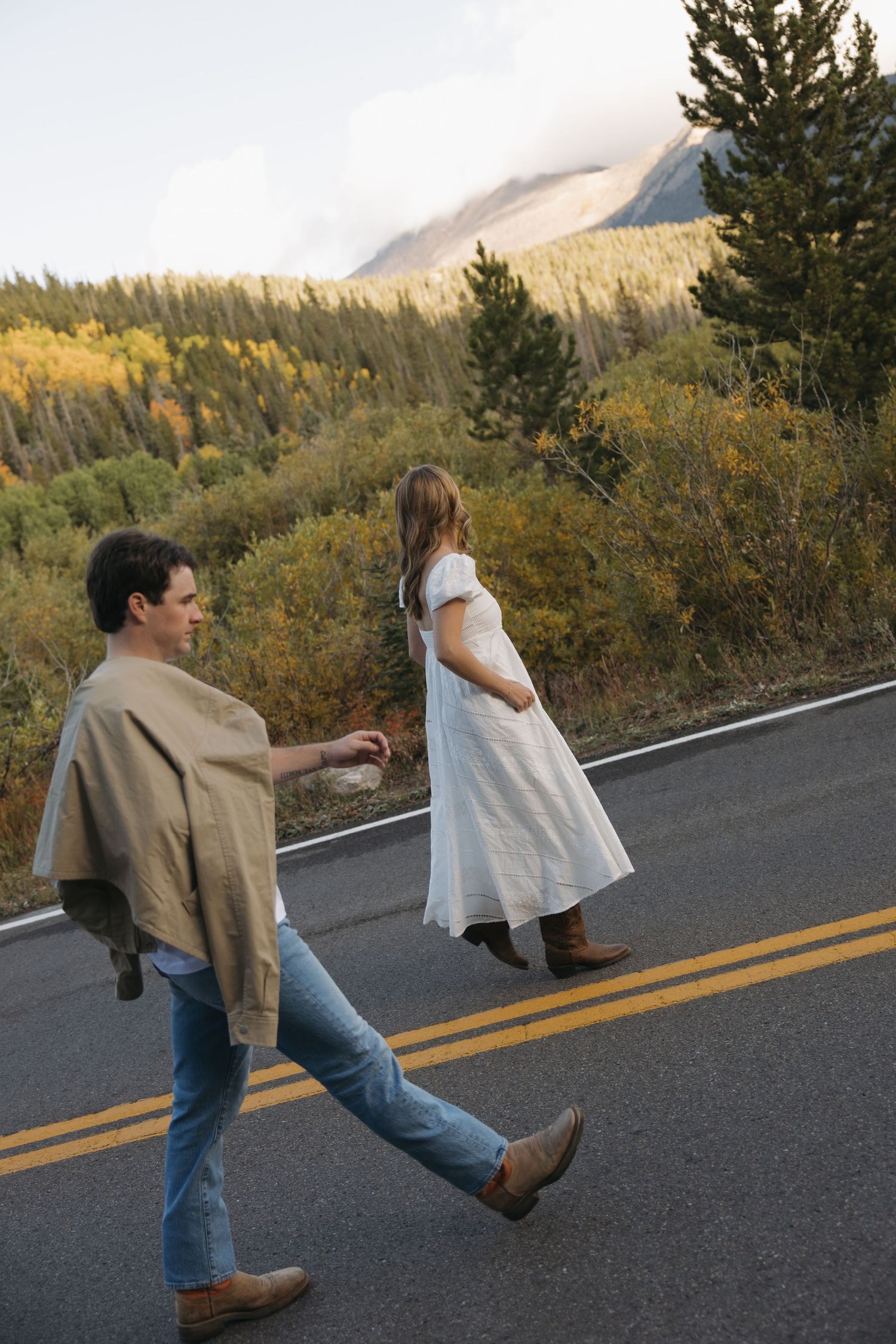A sequence of photos showing two people dancing and spinning on a mountain road surrounded by autumn foliage.