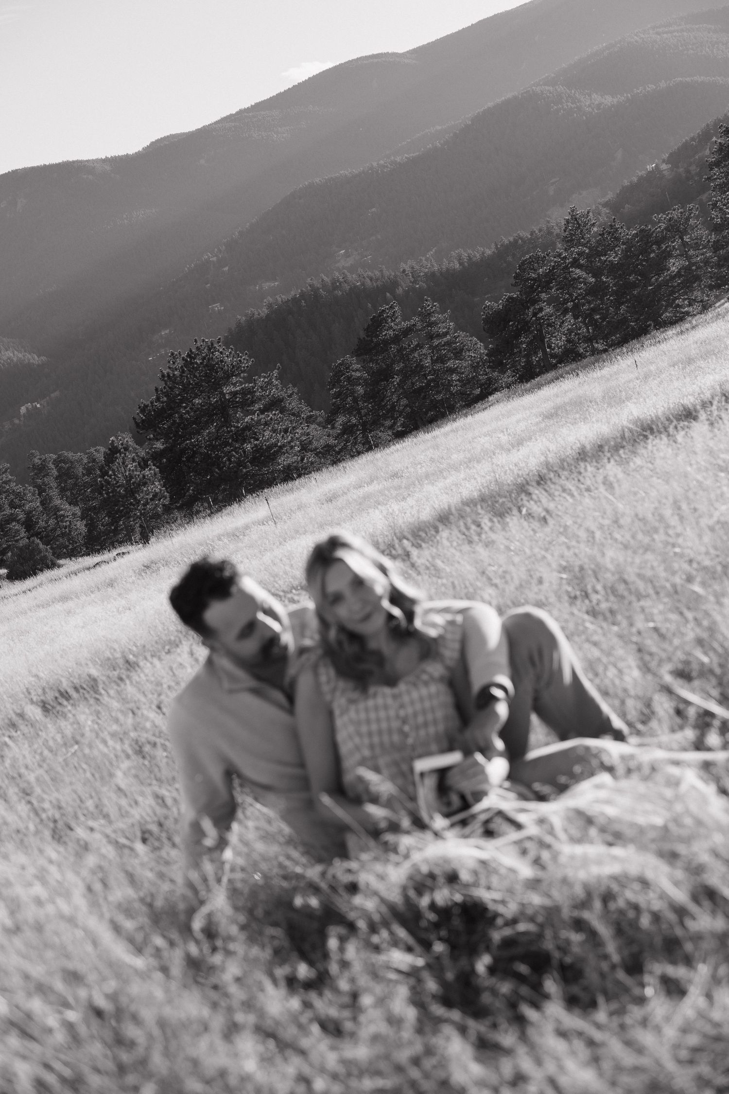 A sequence of black and white photos showing people rolling down a grassy hillside with mountains in the background.