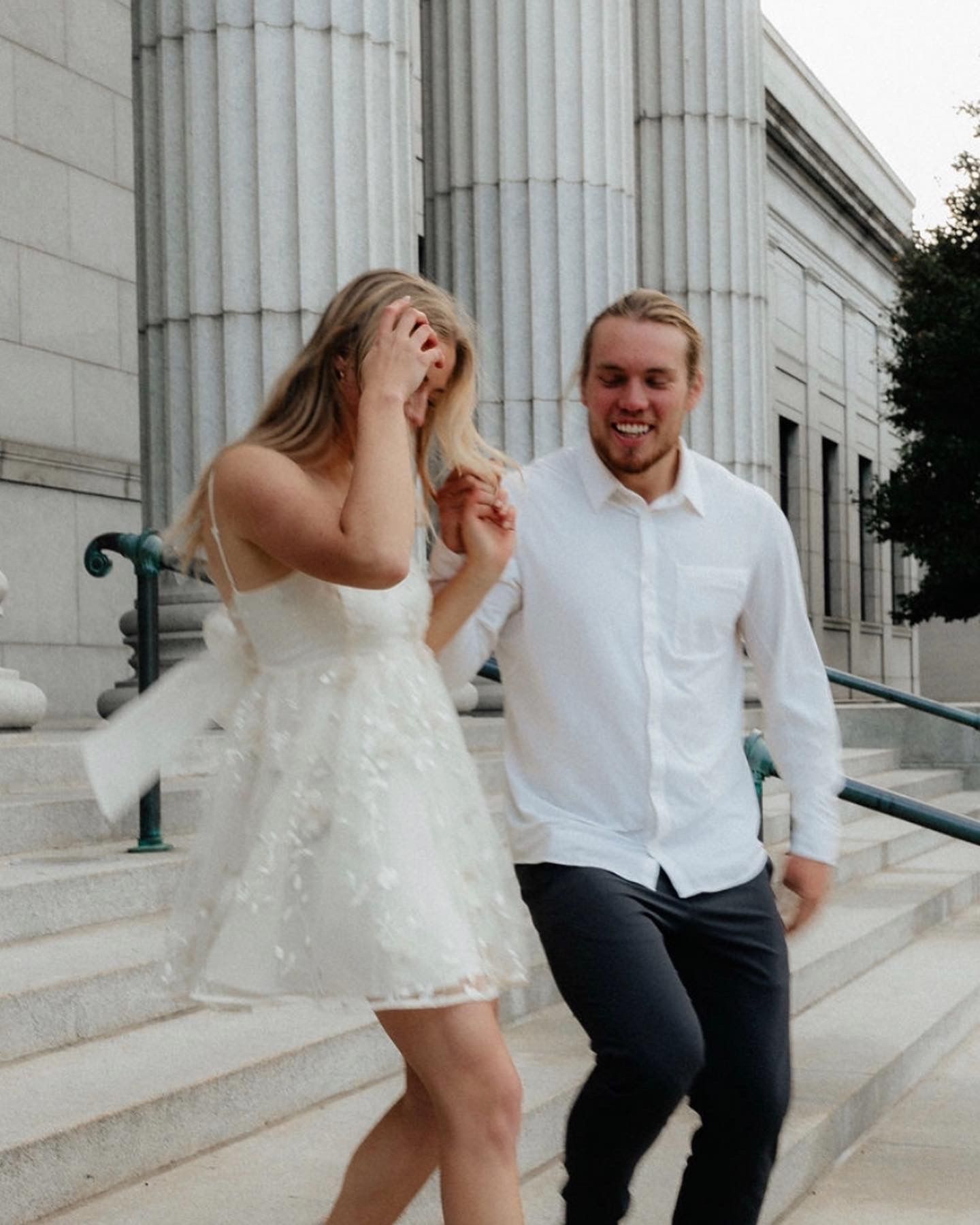 Joyful couple sharing a candid moment on marble steps in the city.