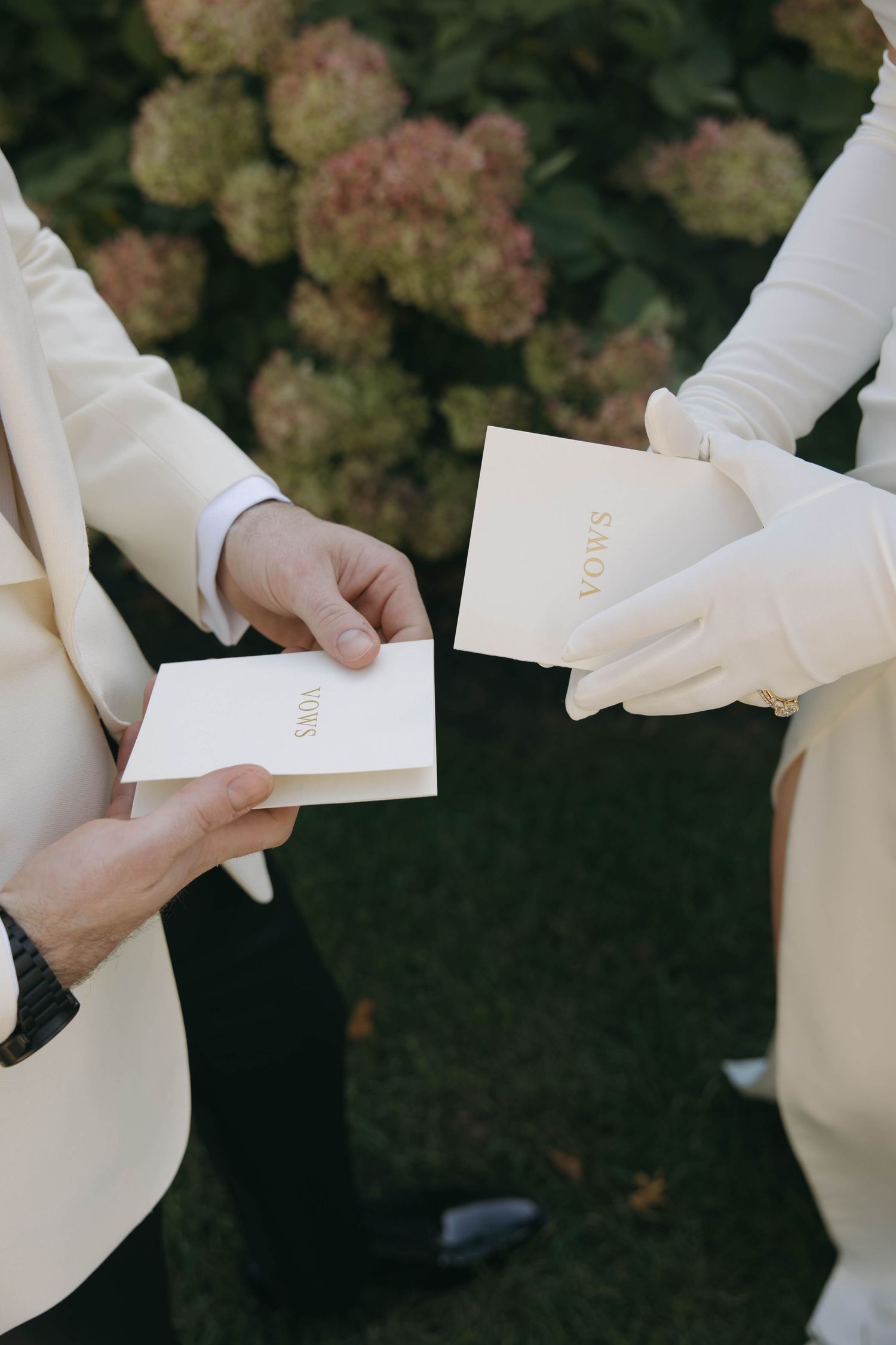 People holding white paper airplanes in their hands against a dark background with blurred autumn foliage.