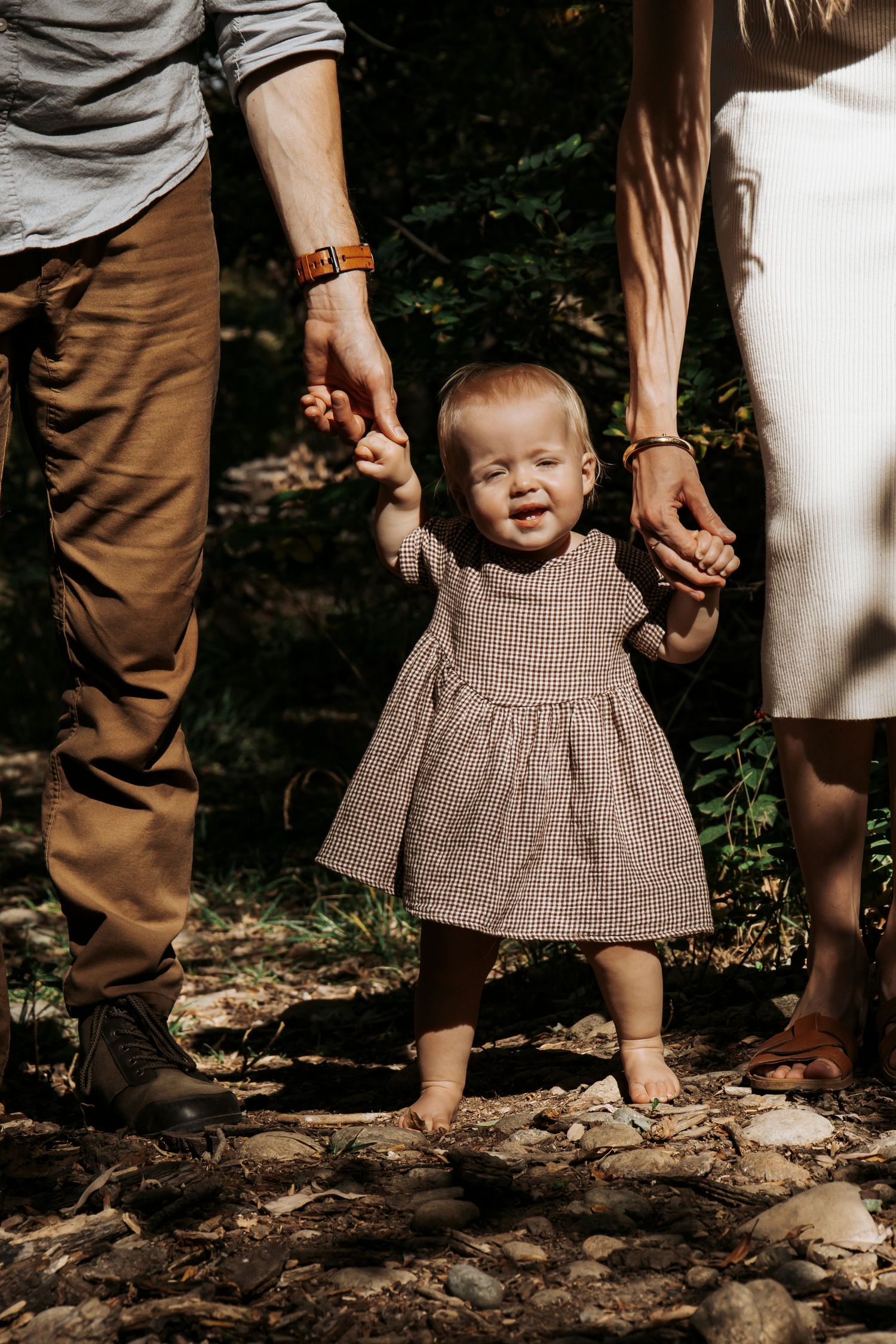 A candid shot showing small feet walking through the woods while wearing a brown knit dress.