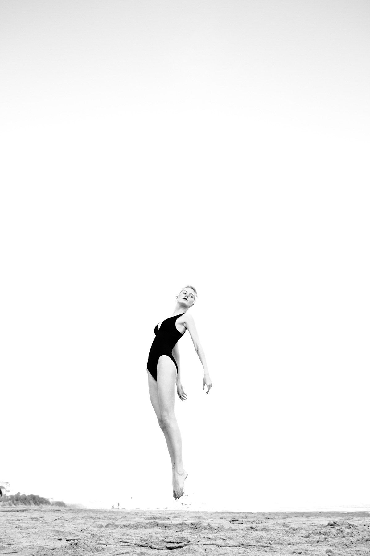 Black and white photo of a woman leaping gracefully on a beach.