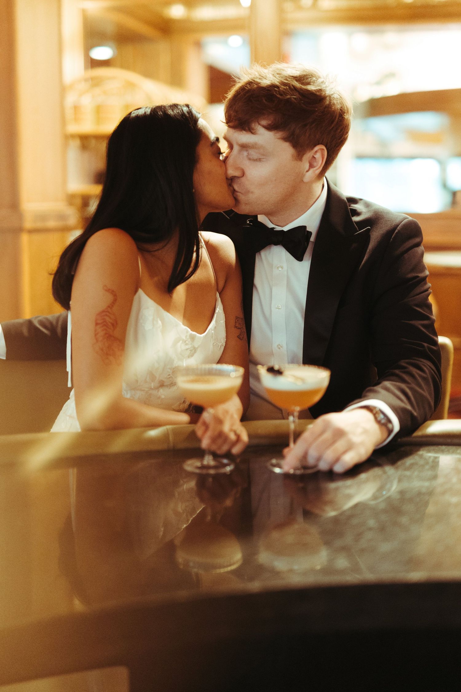 A couple shares intimate moments at a bar counter in warm lighting.