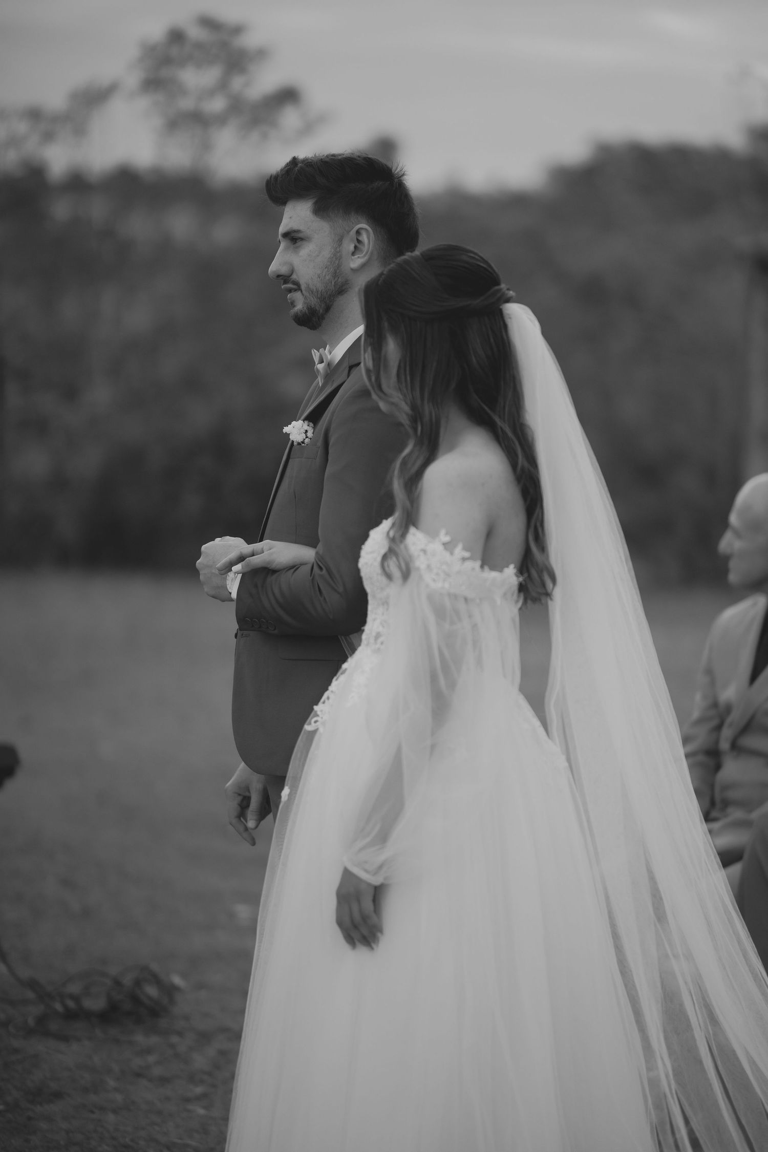 Black and white photo of bride and groom during outdoor wedding ceremony.