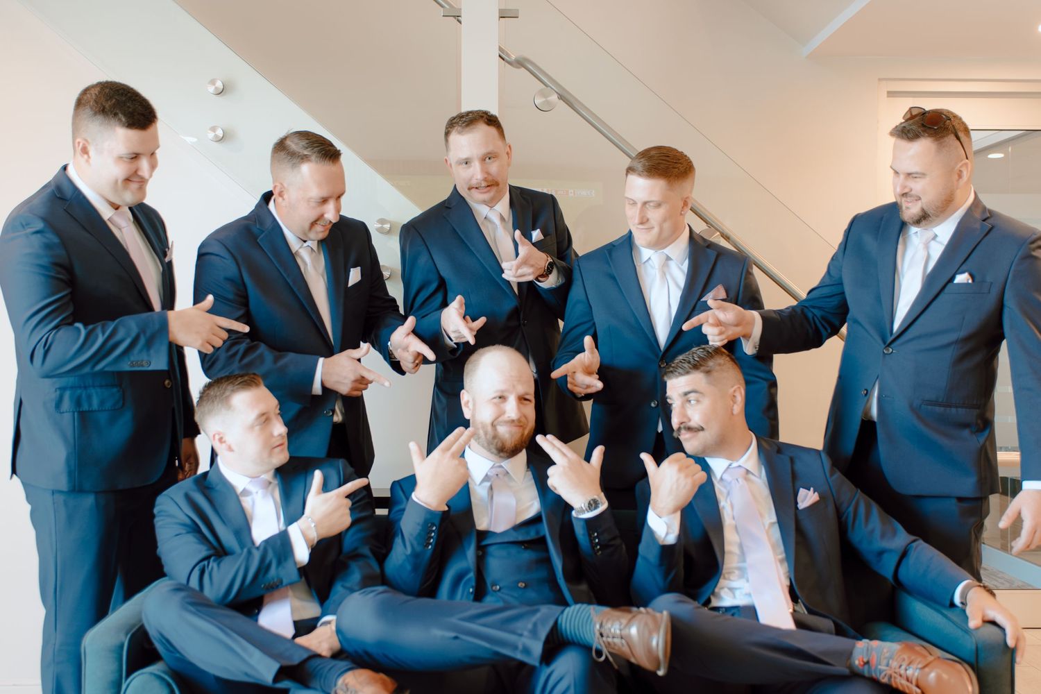 Groomsmen in navy suits laughing and posing together before a wedding ceremony.