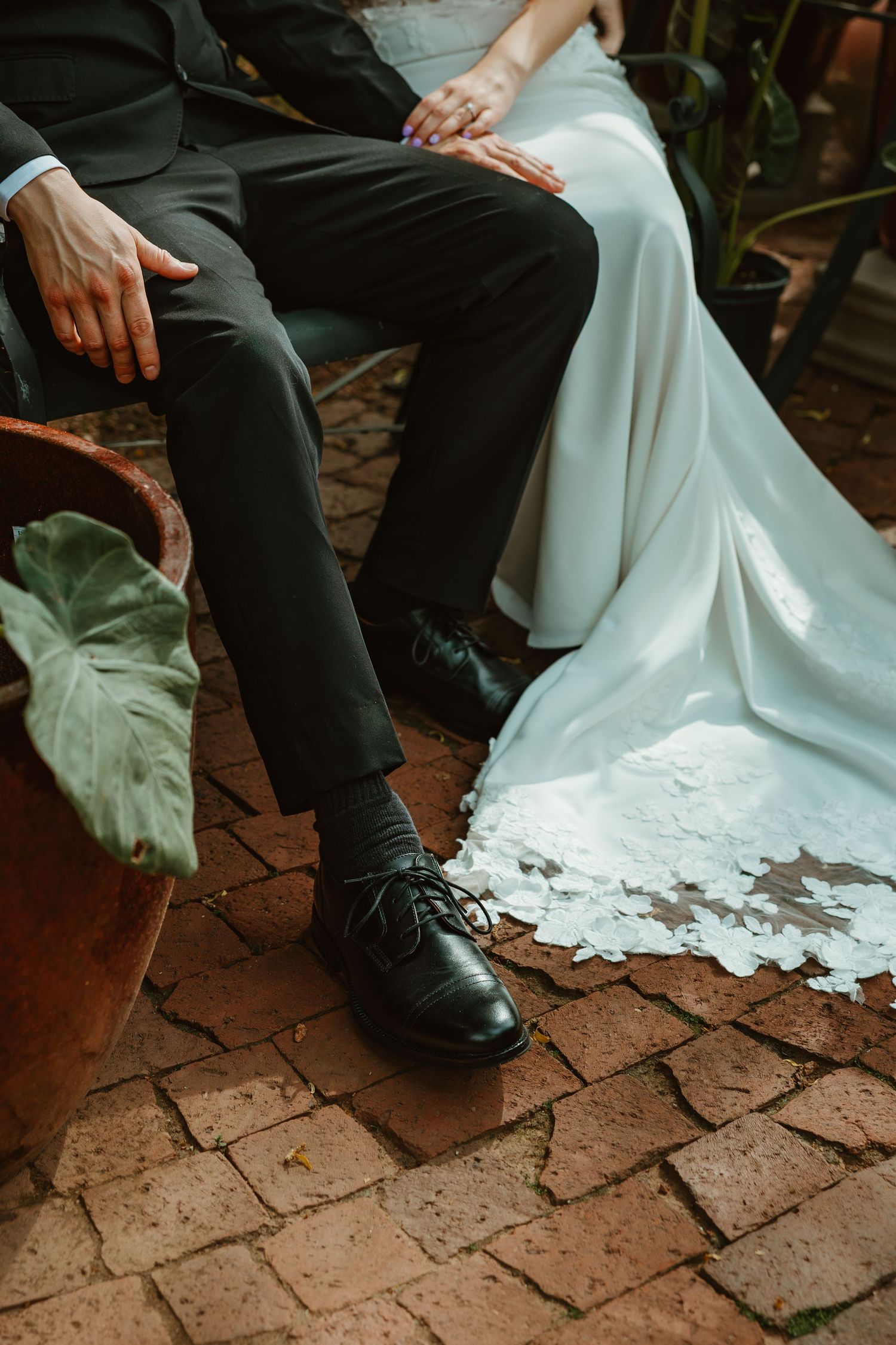 Bride and groom seated on bench showing wedding dress lace hem and groom's black dress shoes. Chicagoland wedding venues.
