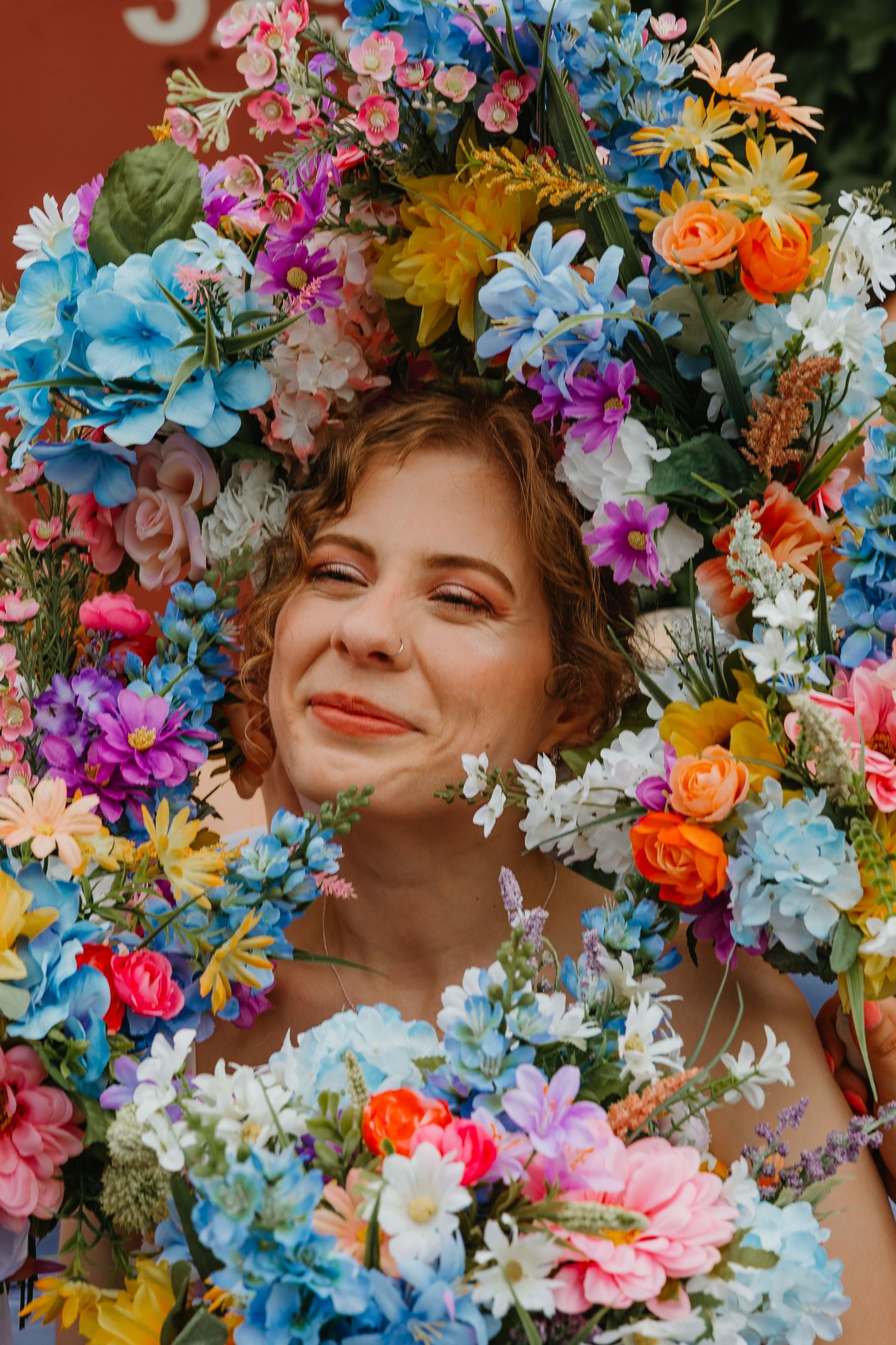 Smiling bride surrounded by a large colorful floral wreath with vibrant mixed blooms. Chicagoland wedding venues.
