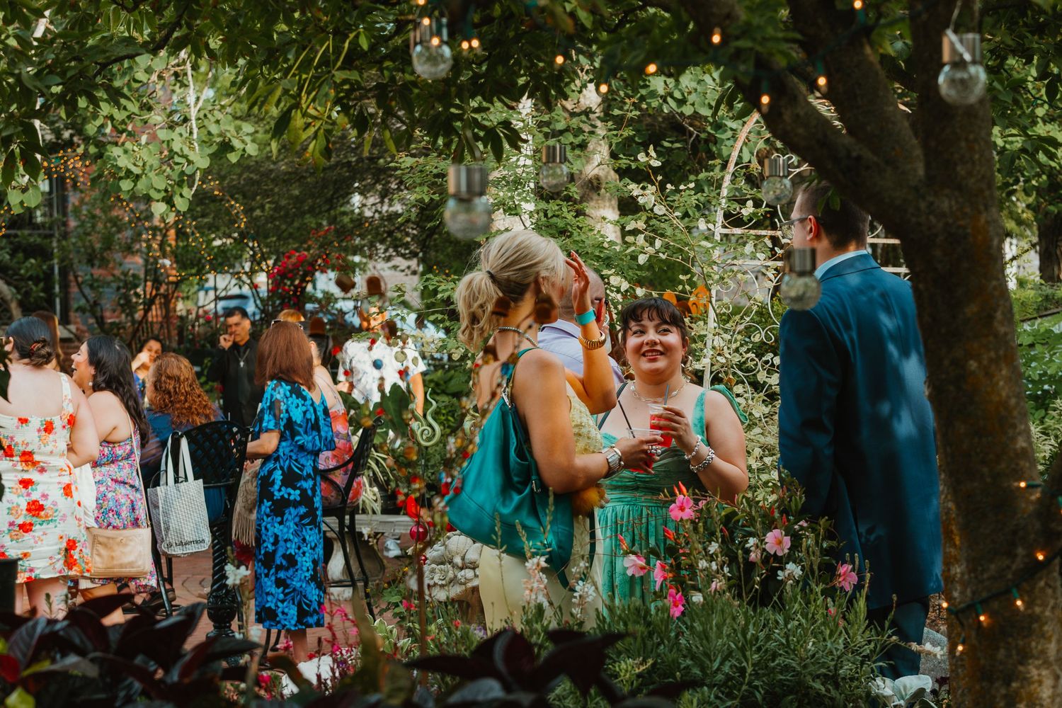 Guests mingle and socialize at an outdoor garden wedding reception with string lights and flowers. Chicagoland wedding venues.