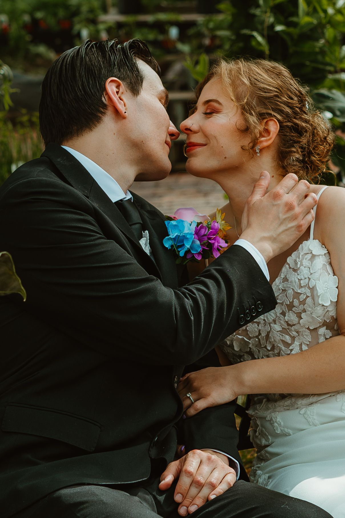 Groom tenderly cups bride's face as they lean in for a kiss in garden setting. Chicagoland wedding venues.