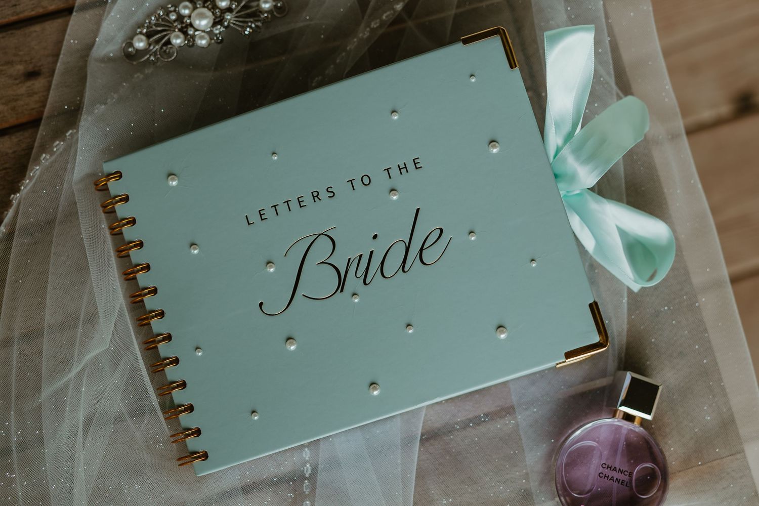 Mint green spiral-bound Letters to the Bride journal with gold accents and teal bow on veil. Northwest Indiana wedding venues.
