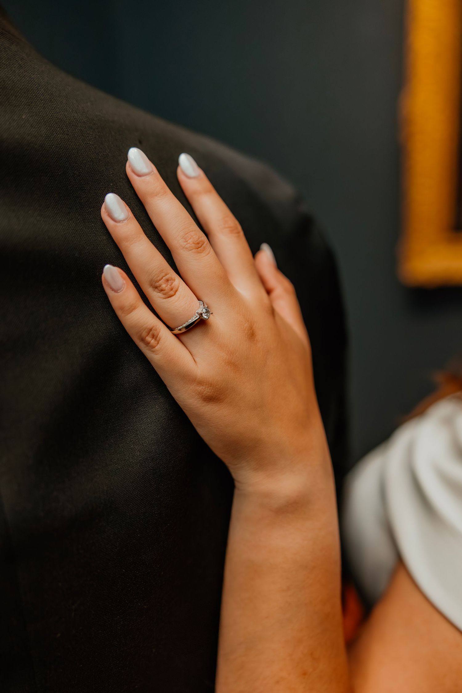 Close-up of womans hand with diamond engagement ring resting on partners back. Art Institute engagement photos.