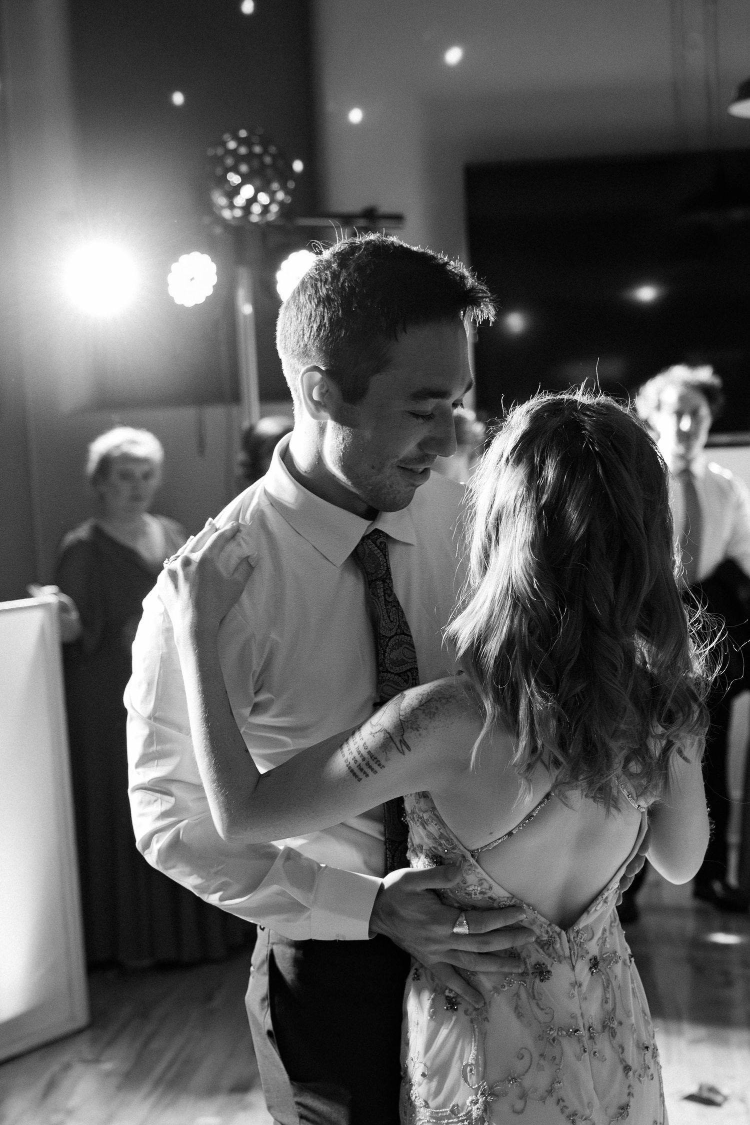 Black and white photo of couple slow dancing closely at their wedding reception.
