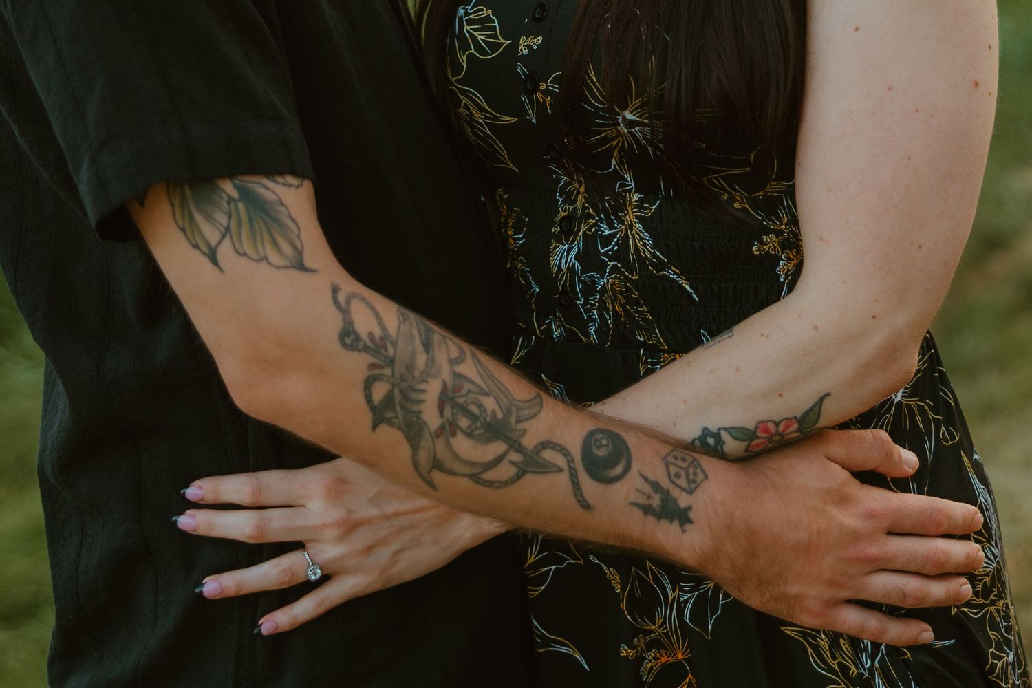 Close-up of a couple's tattooed arms intertwined, with an engagement ring visible on her hand. Chicagoland engagement photos.