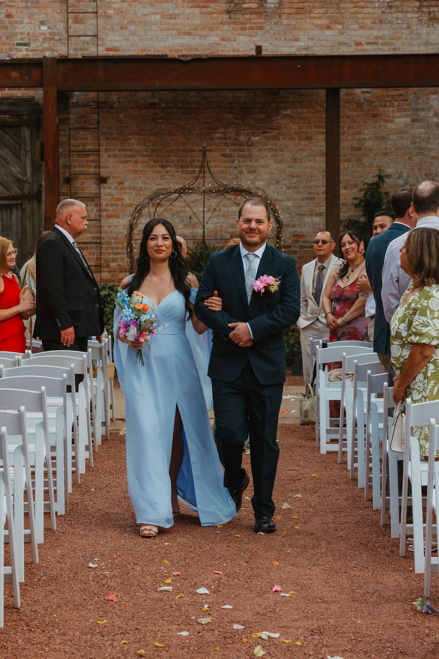 A bridesmaid in a light blue gown walks down the wedding aisle escorted by a groomsman in a dark suit. Chicagoland wedding venues.