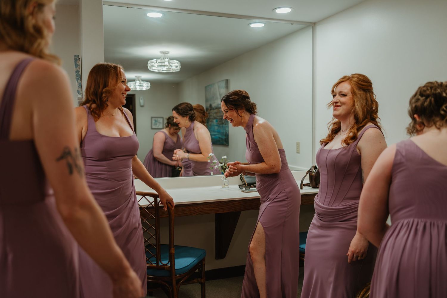 Bridesmaids in dusty purple dresses preparing together in a bridal suite before the wedding ceremony.