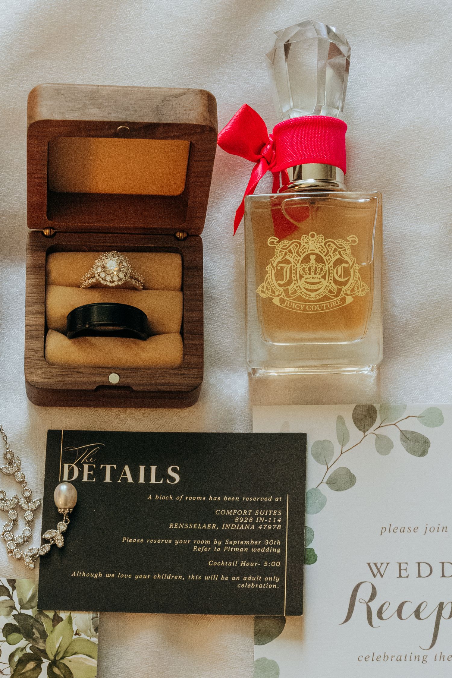 Wedding flat lay with engagement ring, band, perfume bottle, and invitation details. Northwest Indiana wedding venues.