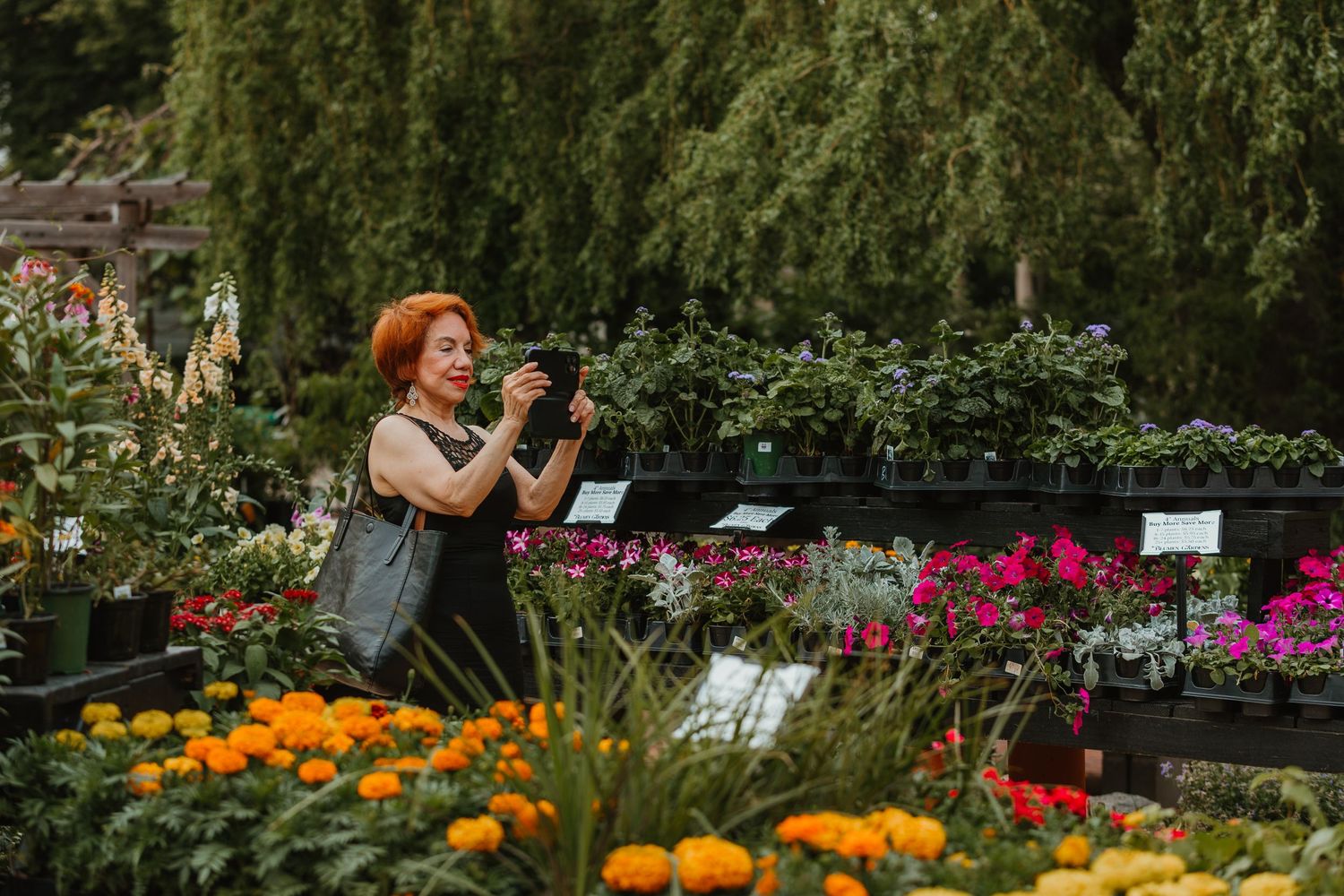 A red-haired woman photographs colorful flowers and plants at an outdoor garden nursery. Chicagoland wedding venues.