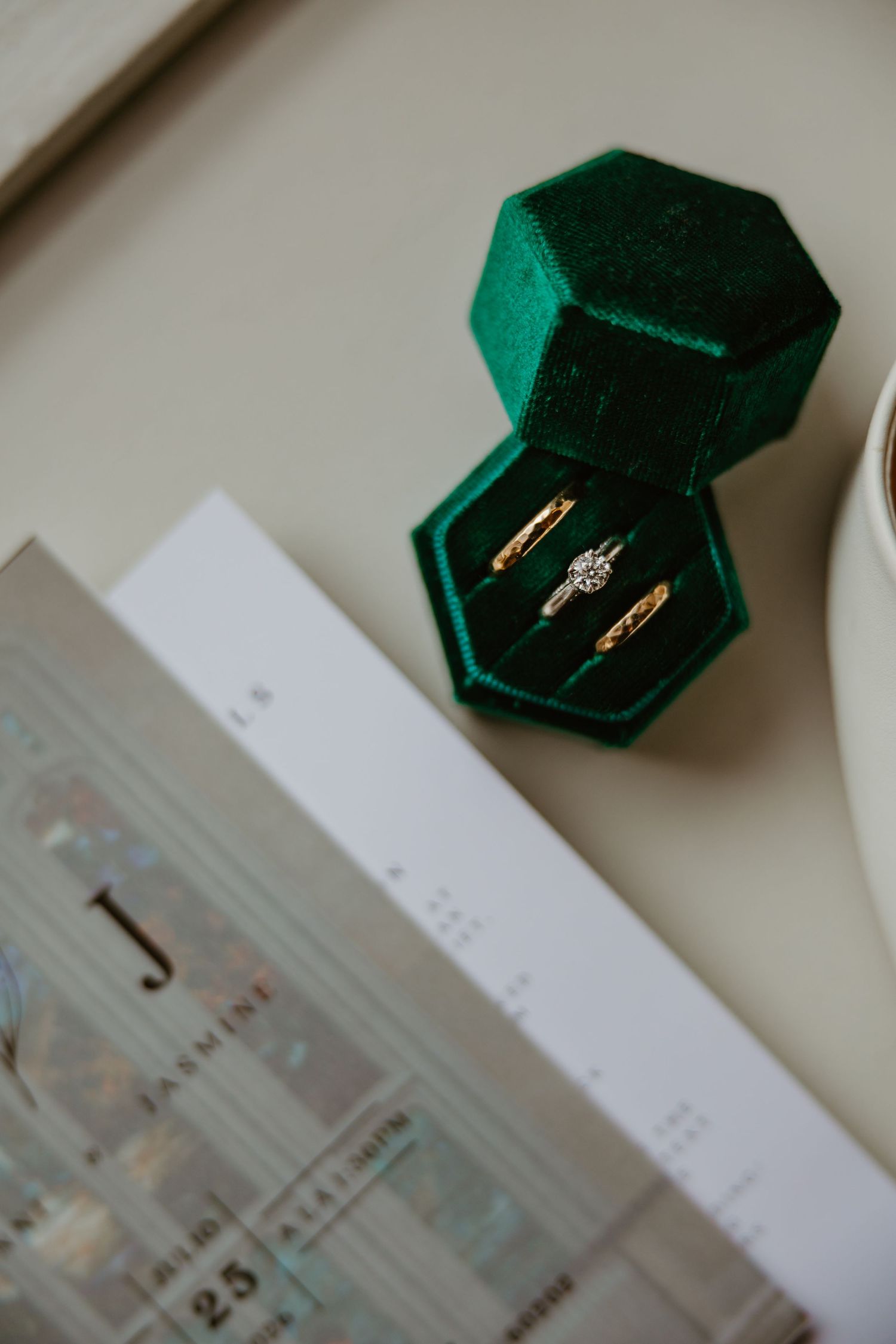 Gold wedding rings and diamond engagement ring displayed in a green velvet hexagon box. Chicagoland weddings.