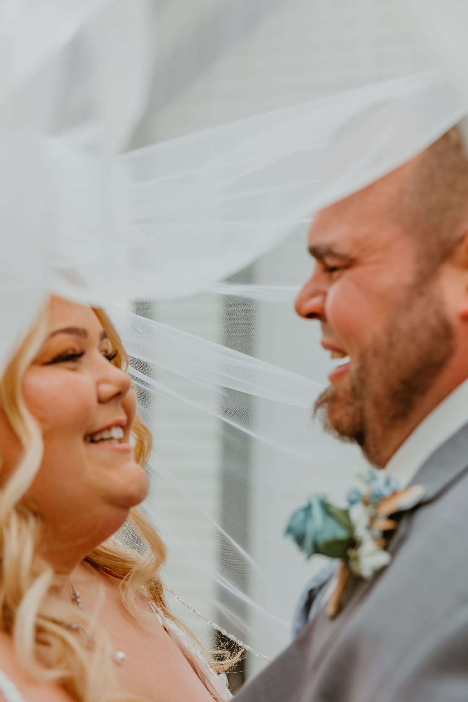 Bride and groom share a joyful moment under a flowing white veil on their wedding day. Northwest Indiana wedding venues.