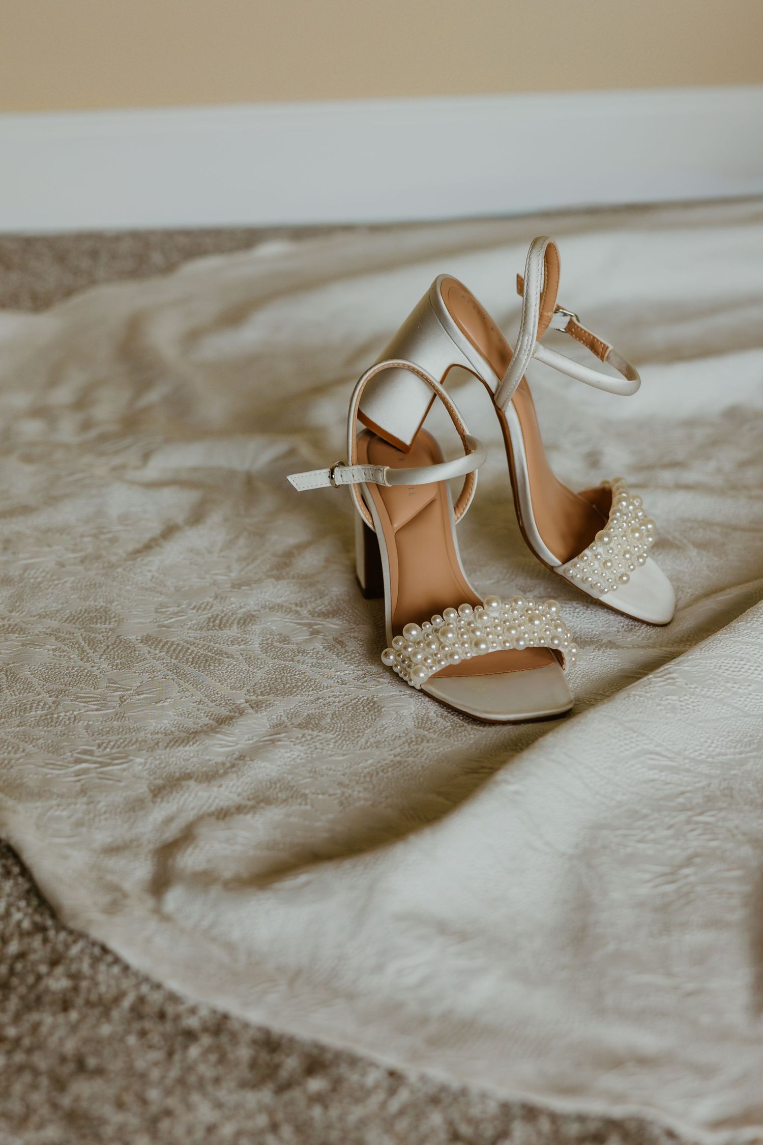Bridal wedding heels adorned with pearl embellishments on cream fabric, perfect for an elegant wedding day look. Chicago documentary style