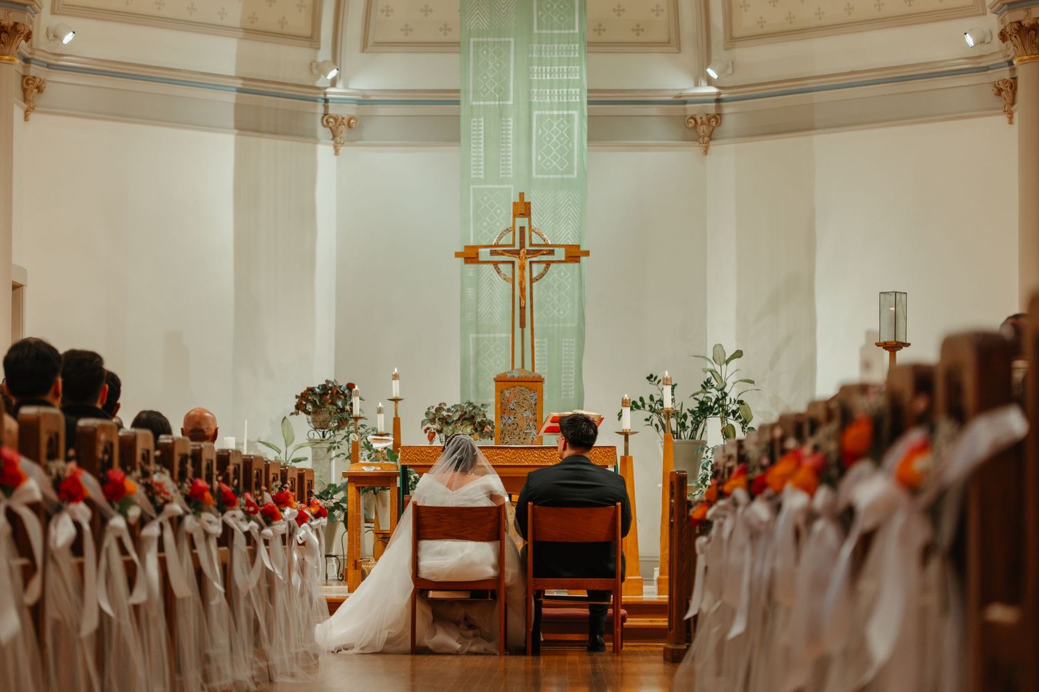 Bride and groom seated at the altar during a traditional Catholic church wedding ceremony. Catholic ceremony in Chicago Catholic Church.
