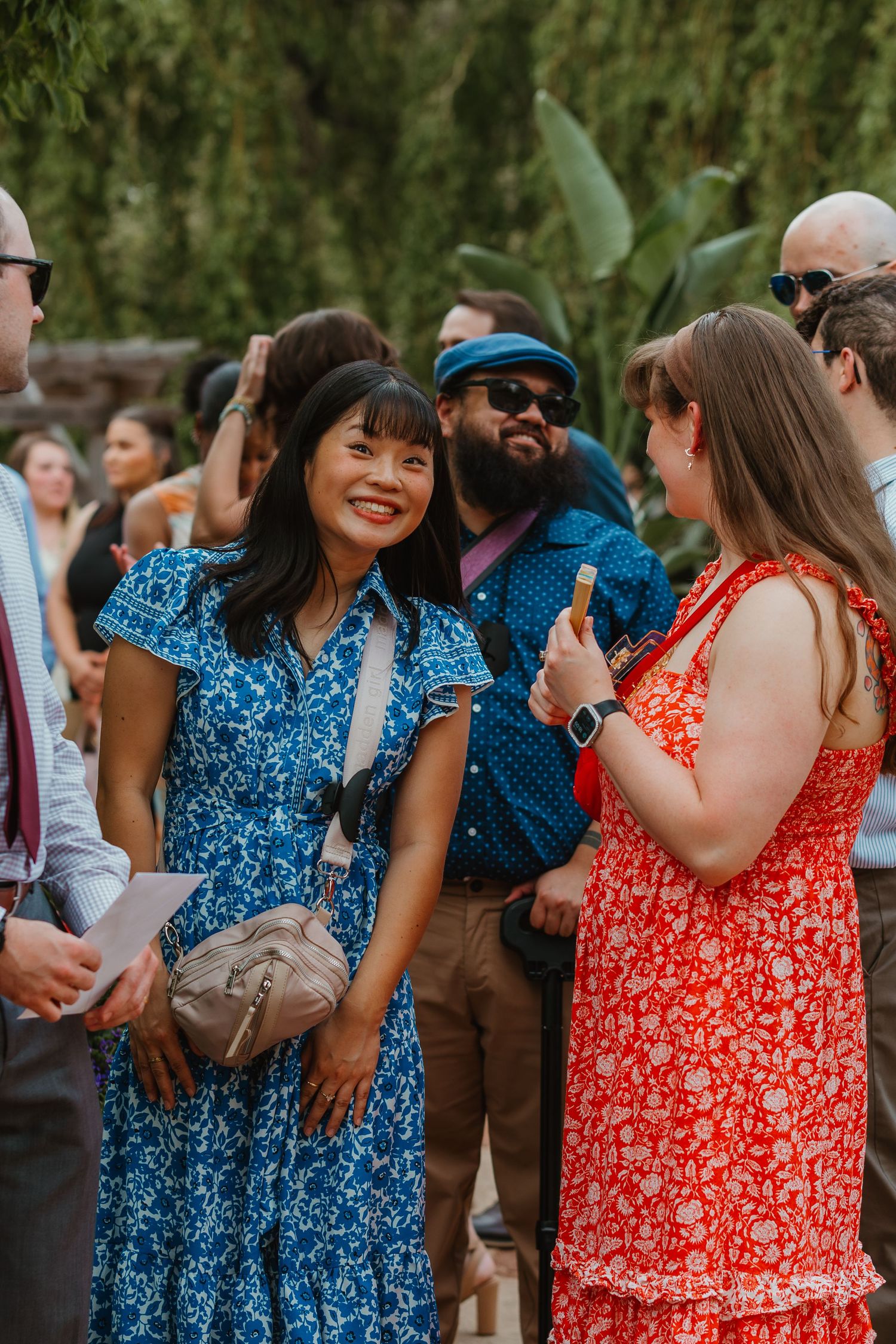 Wedding guests in colorful dresses socializing outdoors in a lush garden ceremony setting. Chicagoland wedding venues.