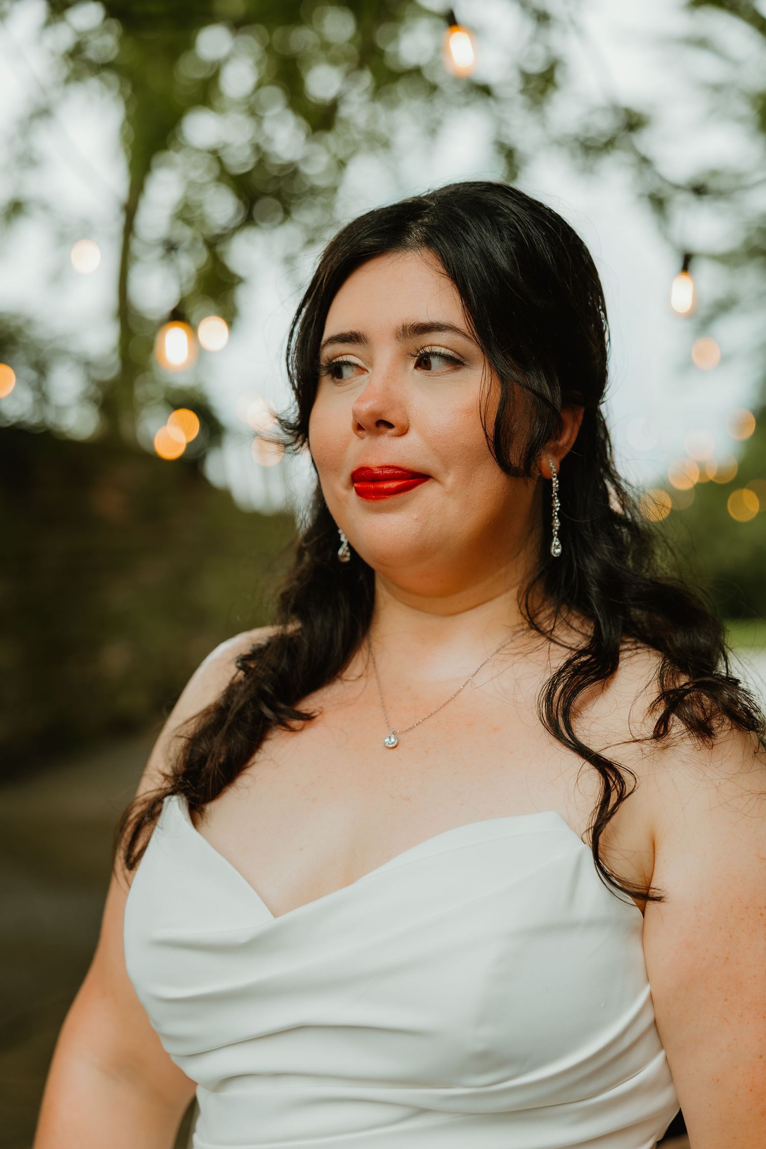 Close-up portrait of bride with red lips, diamond earrings, and white strapless gown at golden hour. Northwest Indiana wedding venues.
