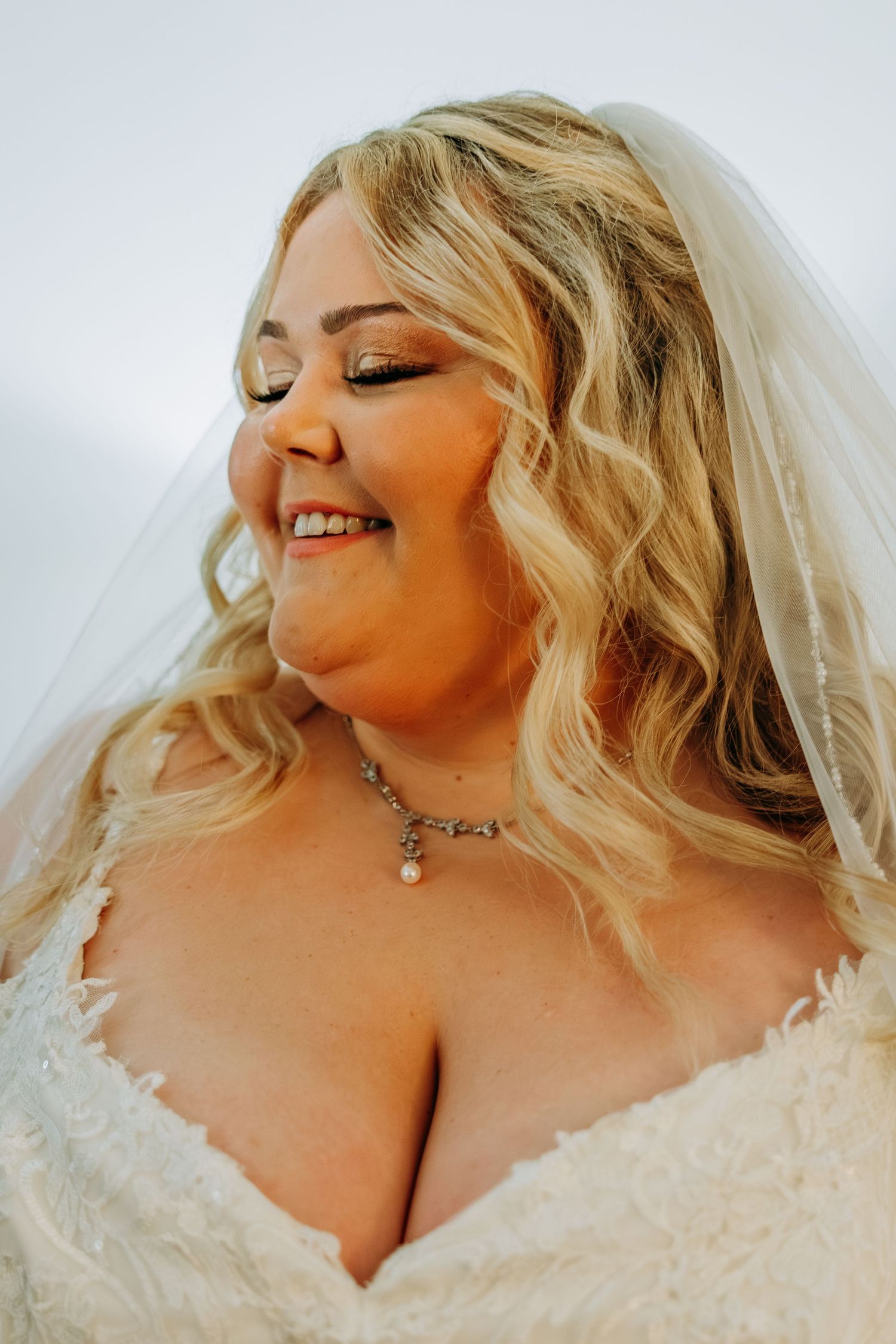 Smiling blonde bride in wedding dress and veil with pearl necklace. Northwest Indiana wedding venues.