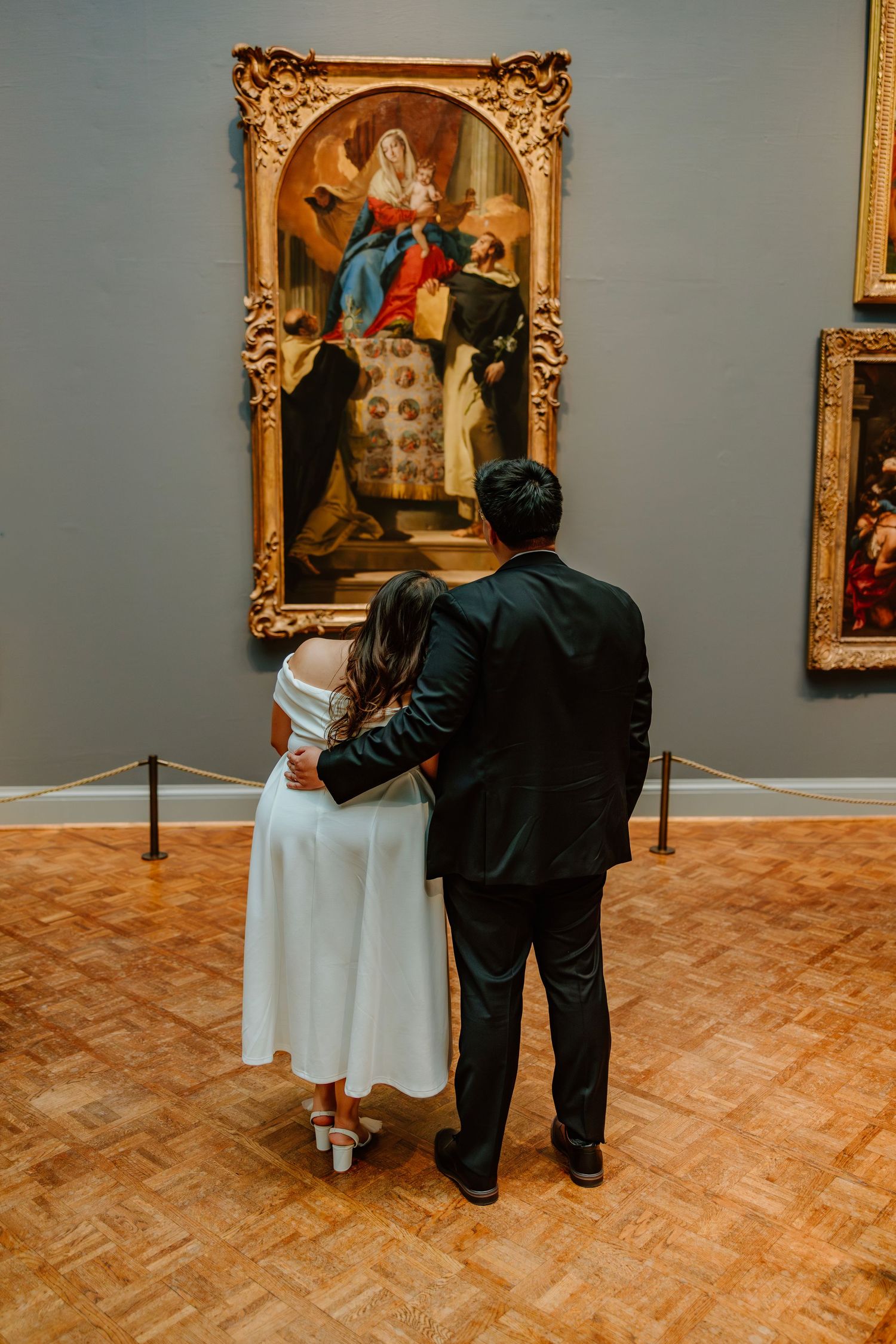 Newlywed couple admiring large gilded religious painting in elegant art museum gallery. Art Institute of Chicago engagement photos.