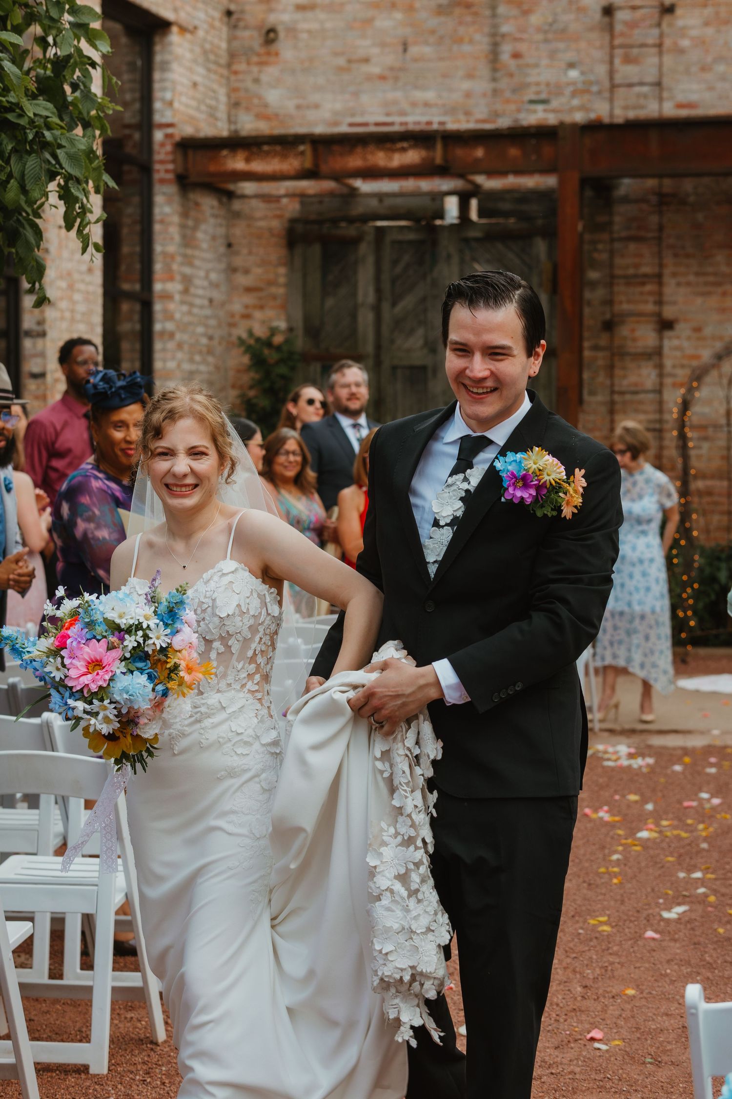 A joyful bride and groom walk back down the aisle after their wedding ceremony amid confetti. Chicagoland wedding venues.