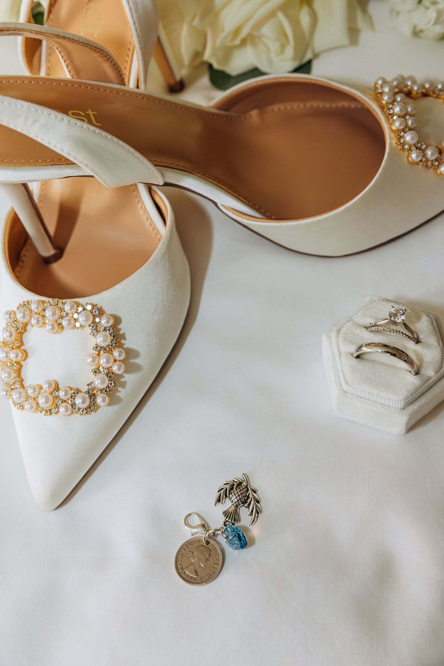 Bridal flat lay with pearl-buckle heels, diamond engagement ring, wedding band, and charm earrings. Chicago hotel wedding photos.