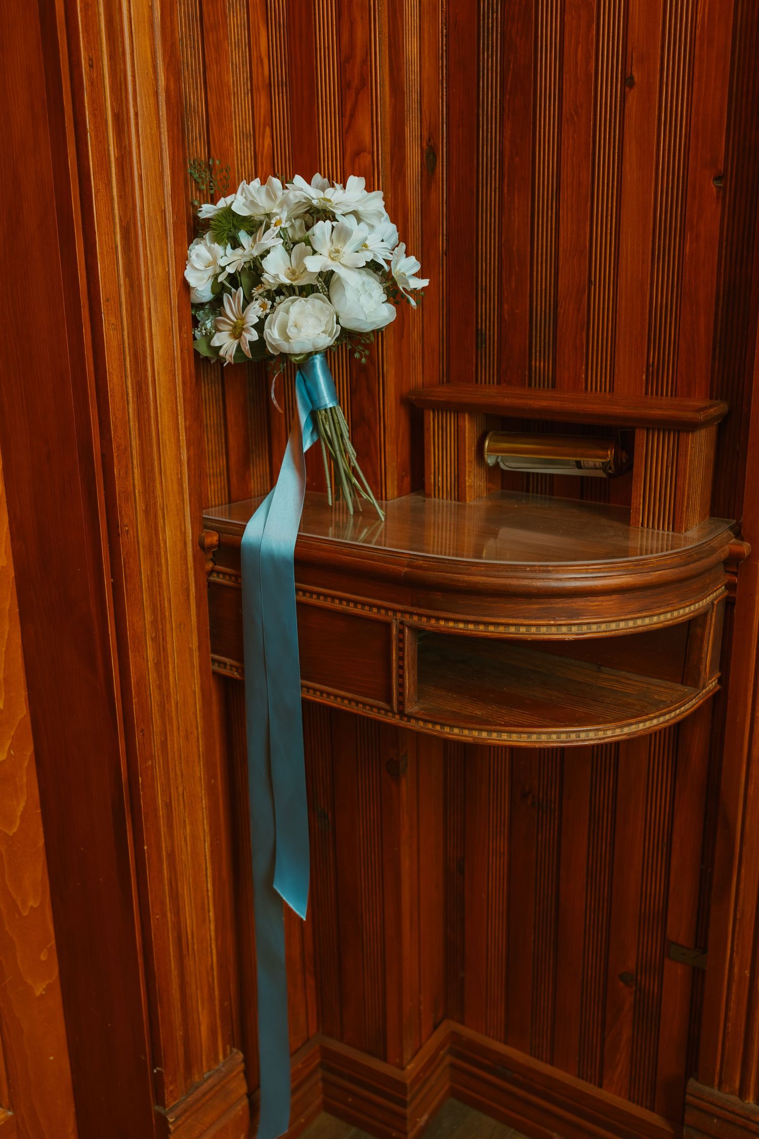 White wedding bouquet with blue ribbon on wooden podium. Michigan elopement.
