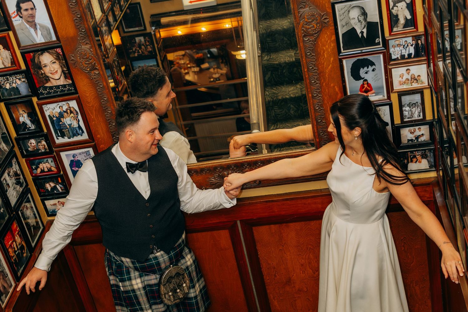 Bride and groom dancing joyfully in a bar filled with framed photos. Chicago wedding reception Gibson's Bar and Steakhouse.