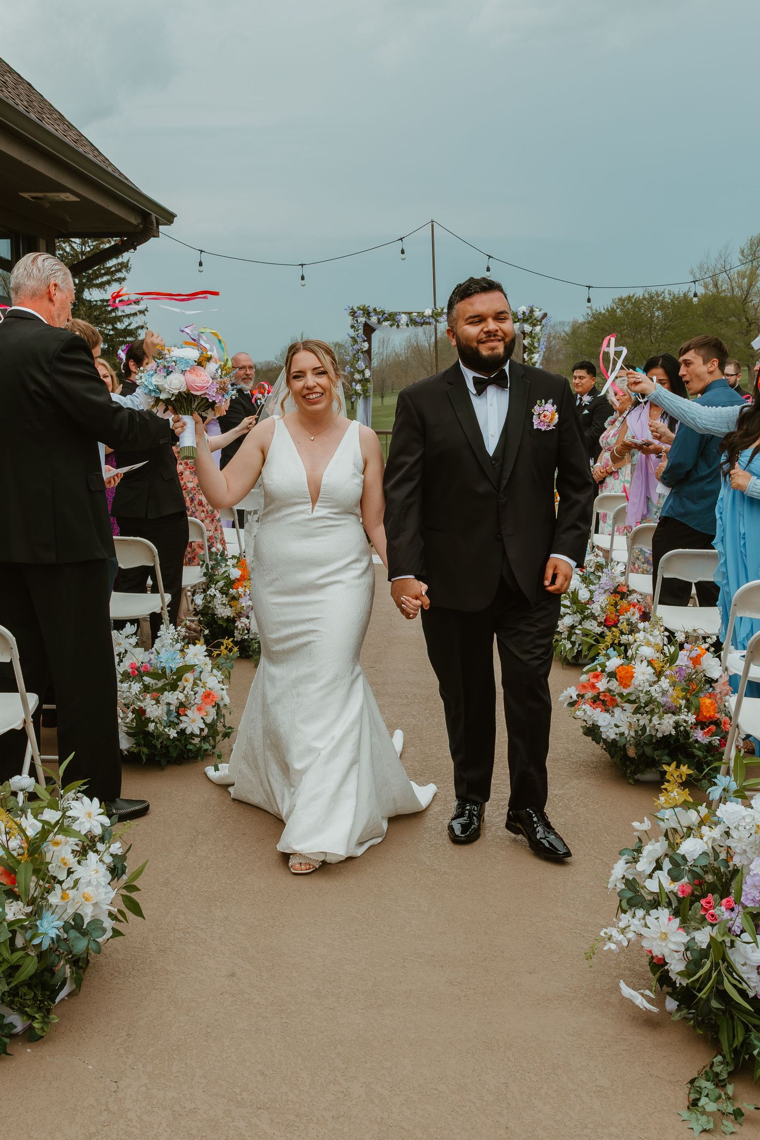 Bride and groom walking down aisle after ceremony surrounded by colorful floral arrangements. Chicagoland wedding venues.