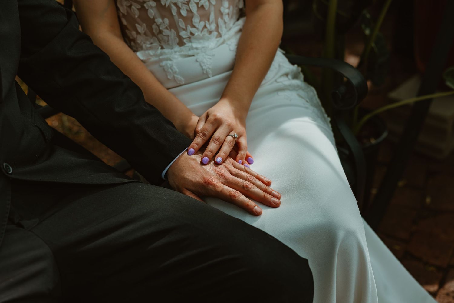 Close-up of bride and groom holding hands showing wedding rings and purple manicure. Chicagoland wedding venues.