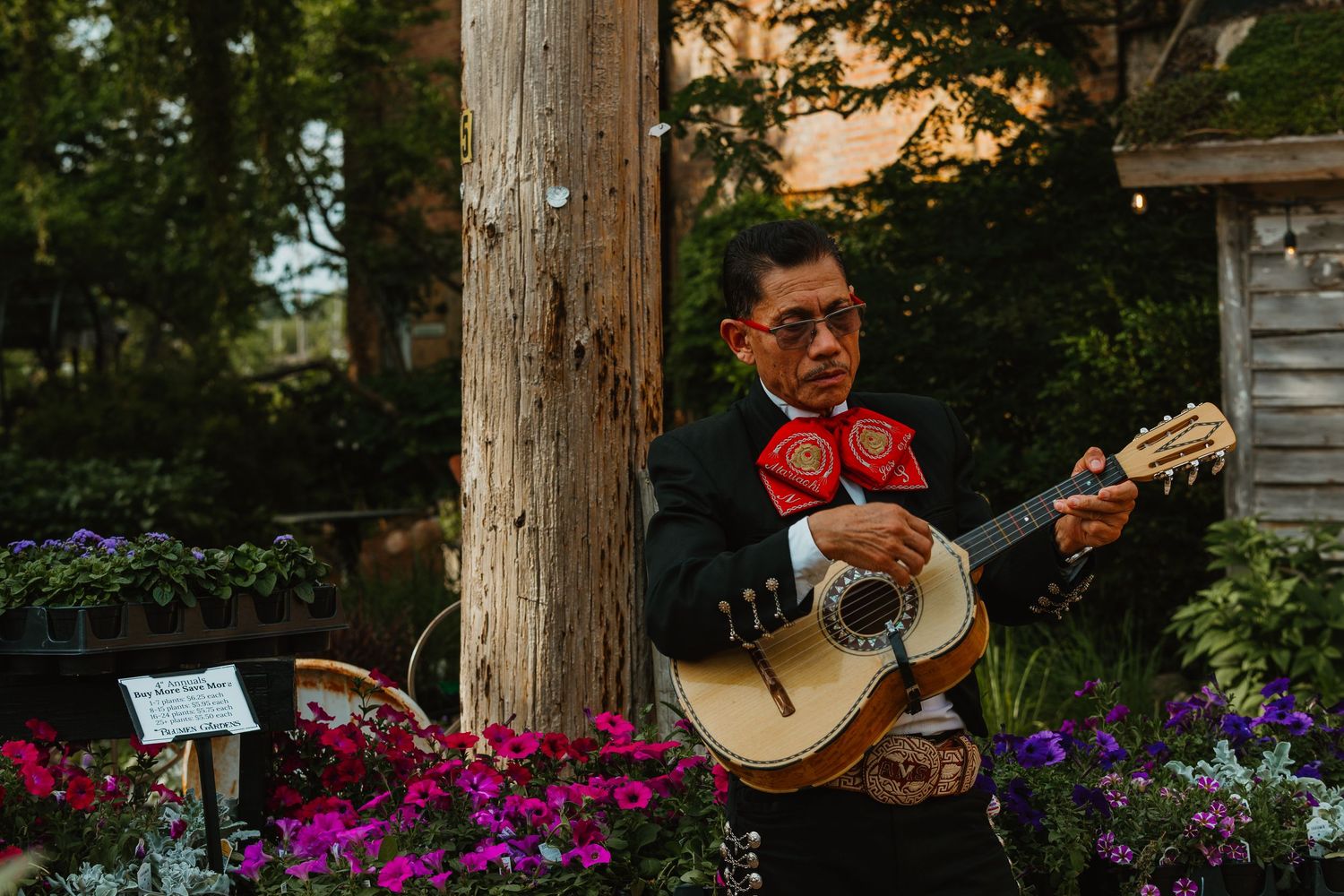 Mariachi musician in traditional black suit playing guitar among vibrant flowers at a wedding. Chicagoland wedding venues.
