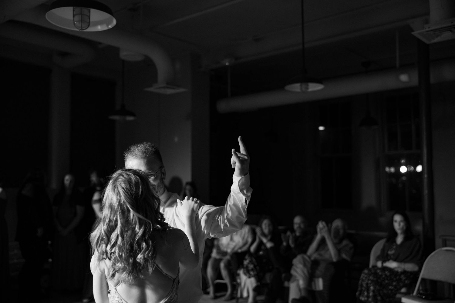 Couple shares first dance at wedding reception in black and white photo.