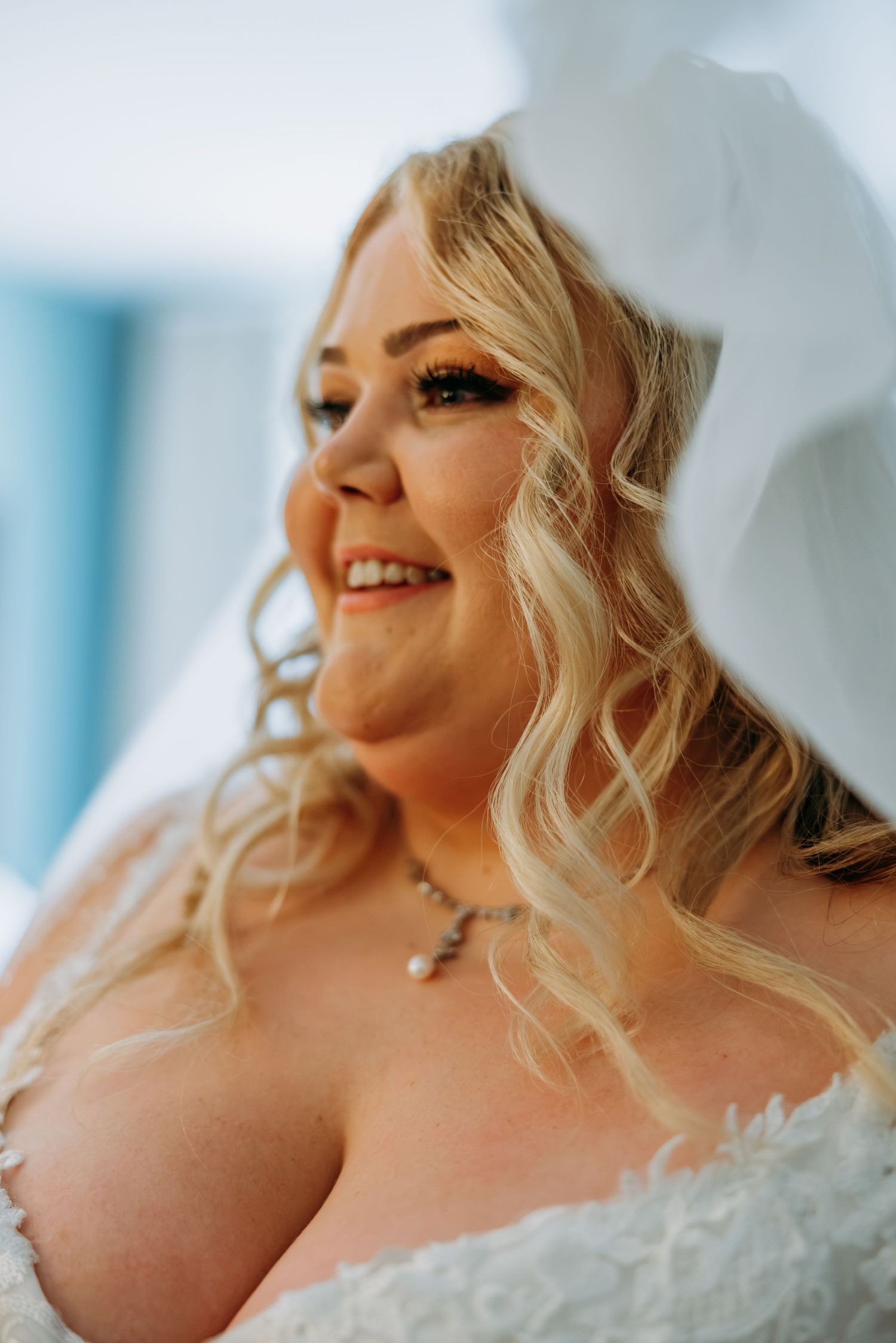 Radiant blonde bride in white wedding dress and veil smiling softly. Northwest Indiana wedding venues.