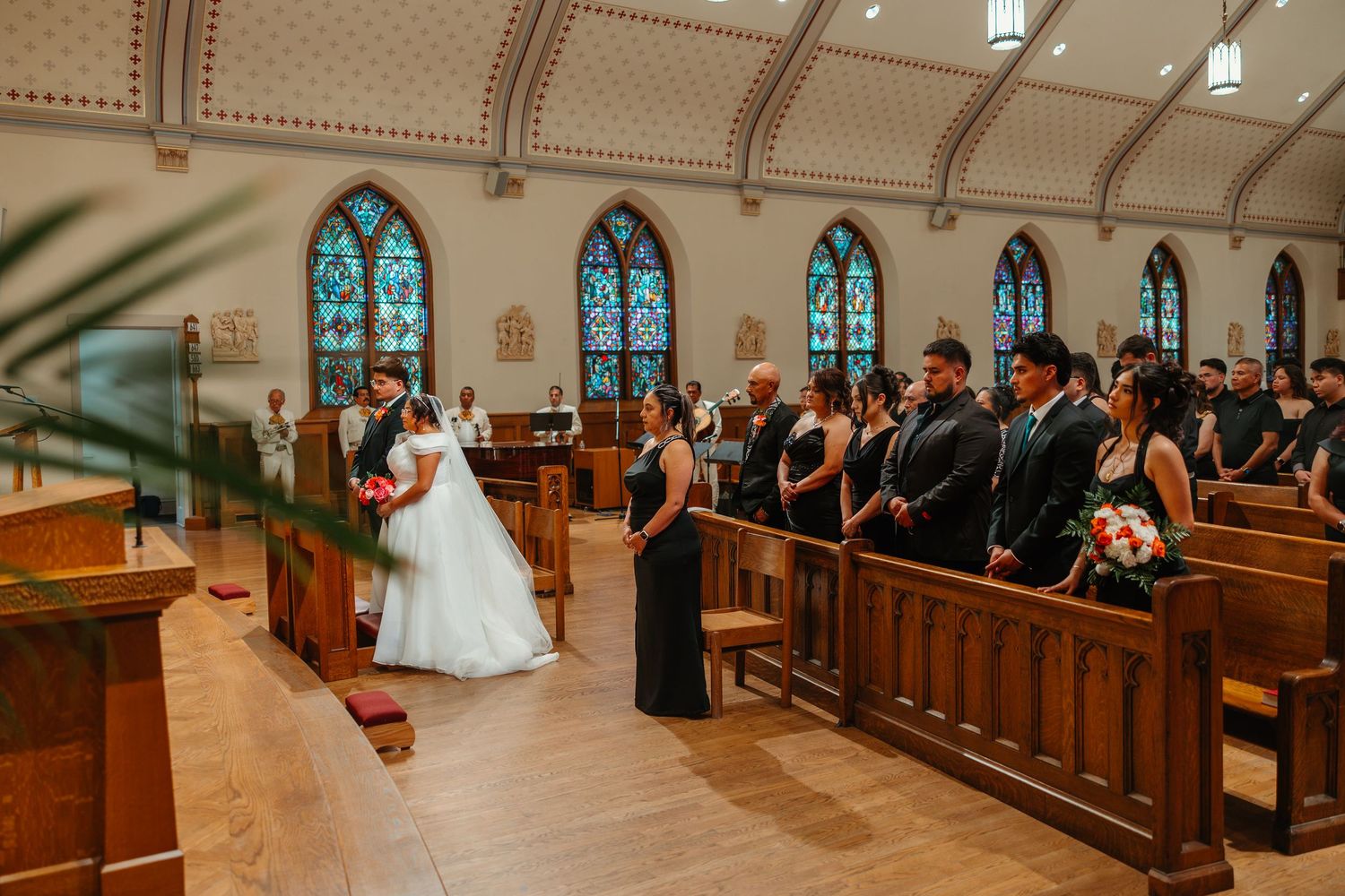 Bride walking down the aisle of a beautiful church with stained glass windows and guests. Catholic ceremony in Chicago Catholic Church.